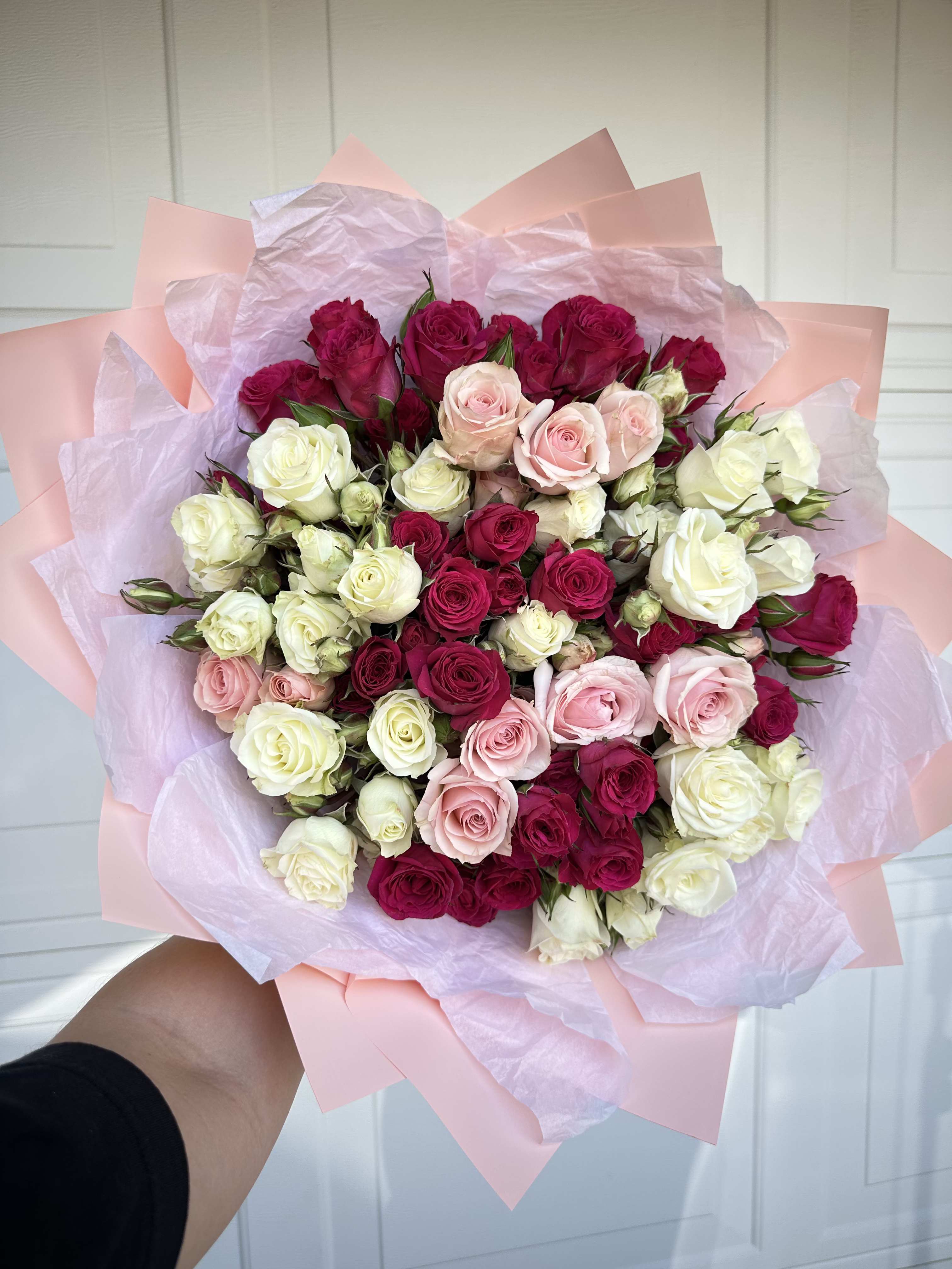 Bouquet of pink, white, and magenta roses wrapped in pastel paper