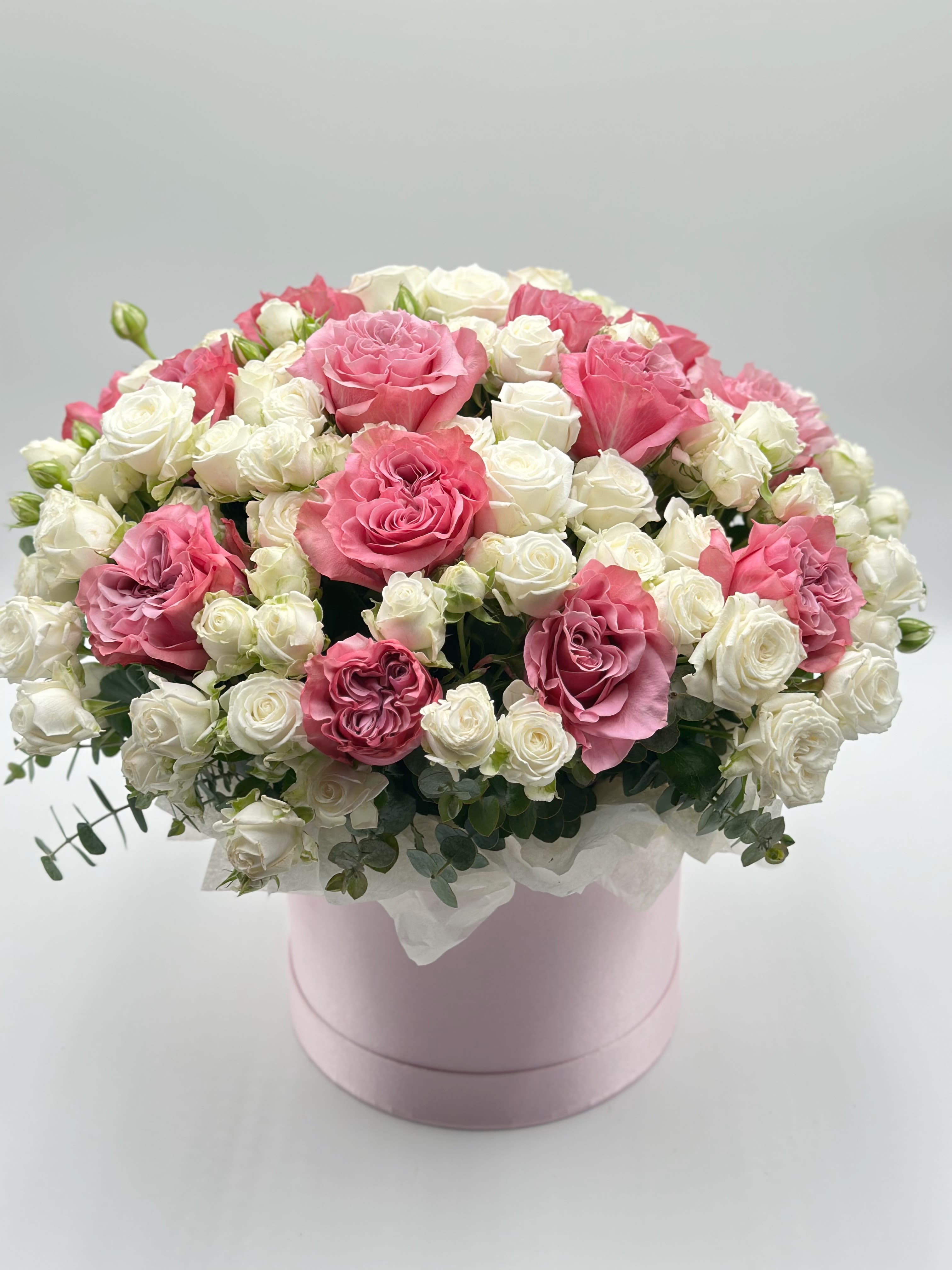 Pink and white roses arranged in a round pink box
