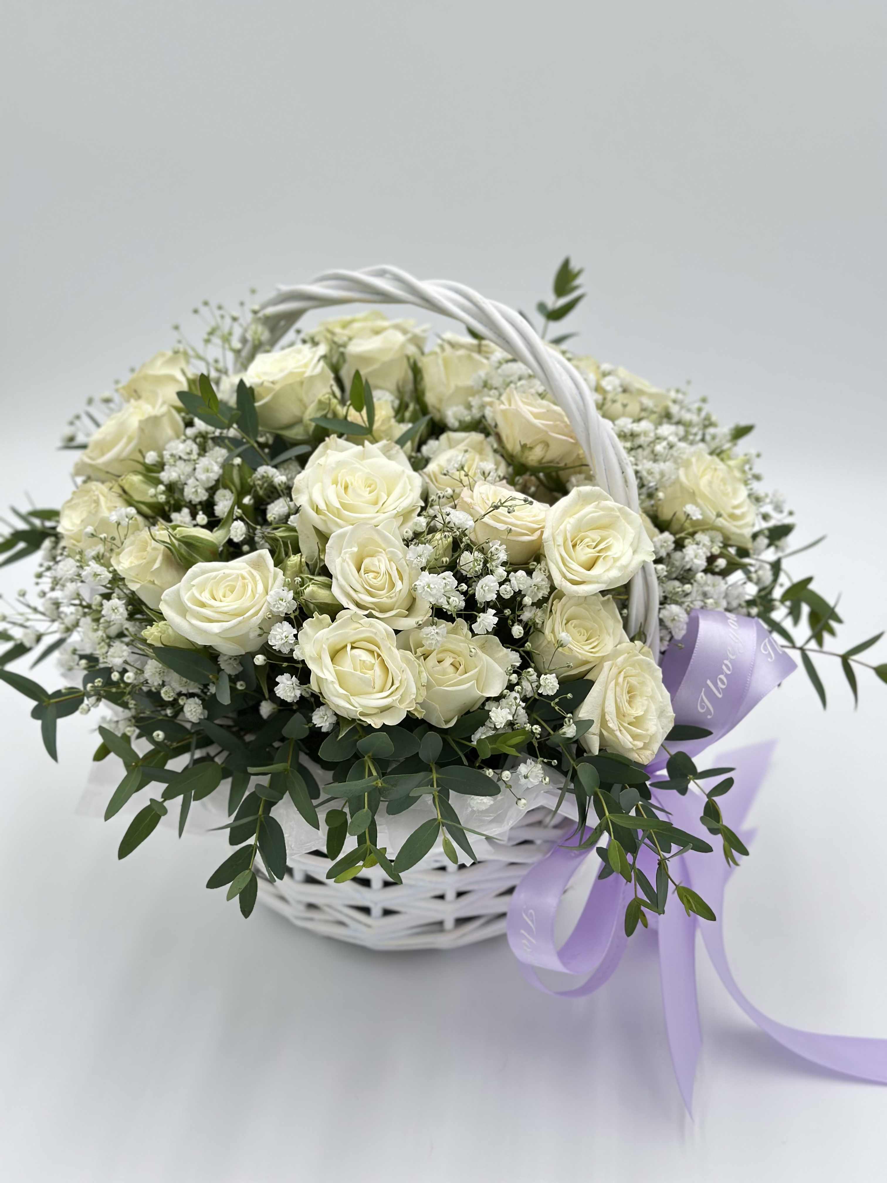 White rose bouquet in a white basket with a lavender ribbon