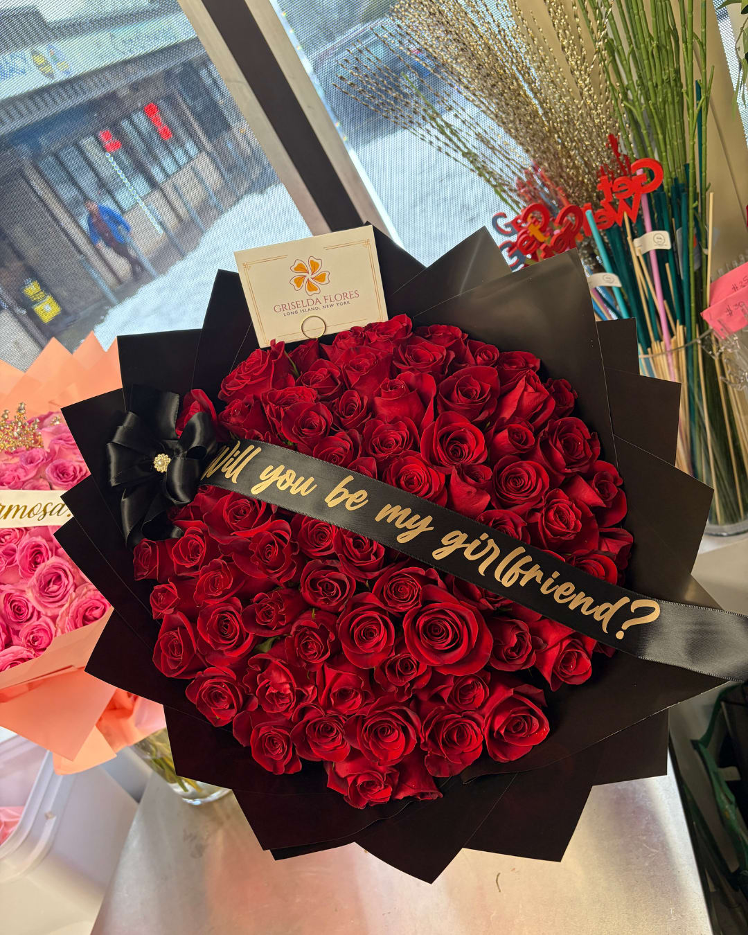 Large bouquet of red roses wrapped in black paper with a ribbon