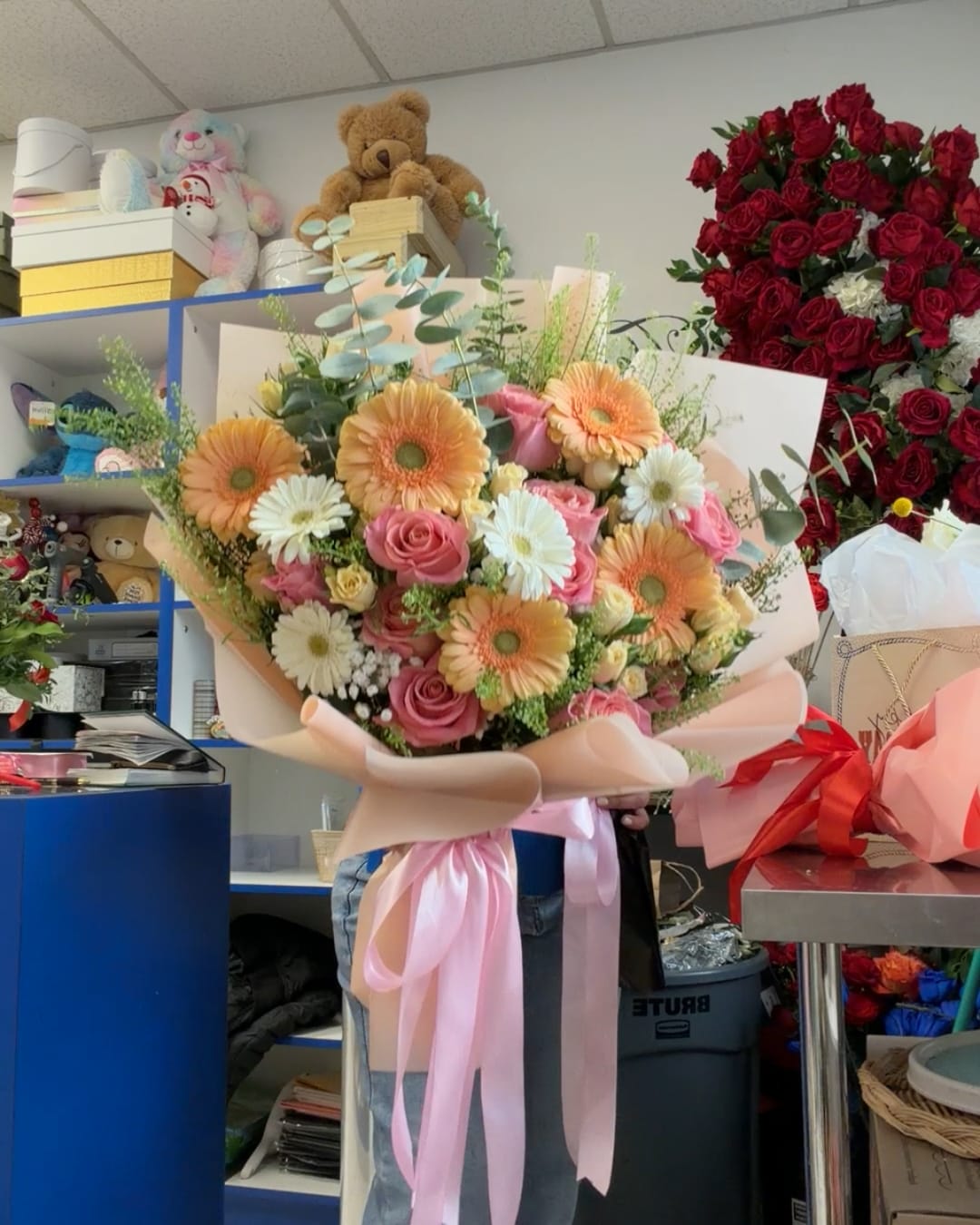 Large bouquet of pink roses and peach gerbera daisies wrapped in blush paper