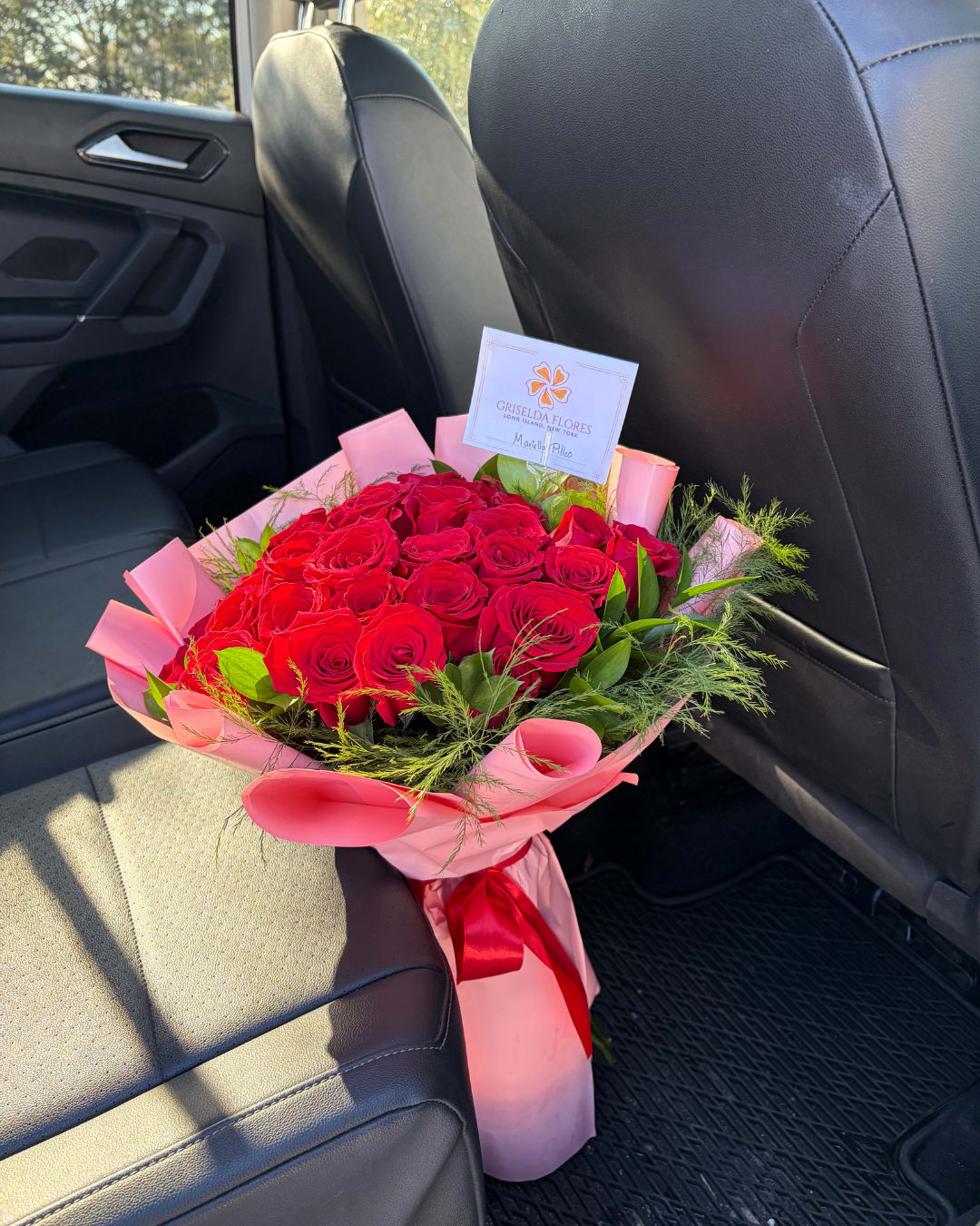 Bouquet of red roses wrapped in pink paper with a red ribbon
