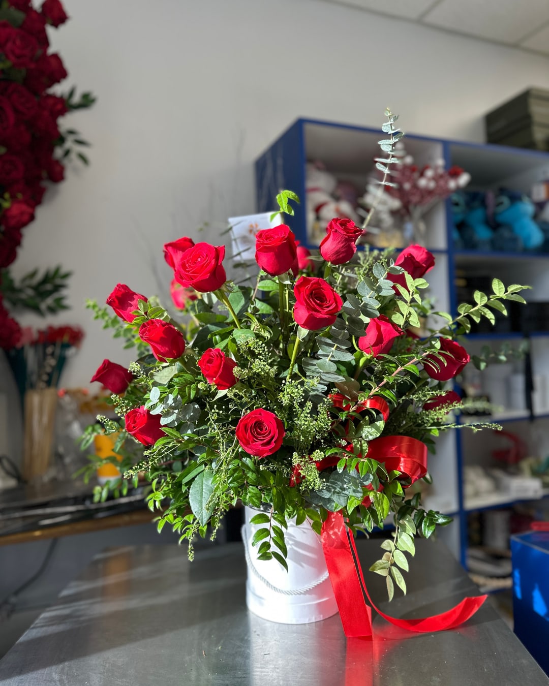 Red roses arranged in a white hatbox with a red ribbon.