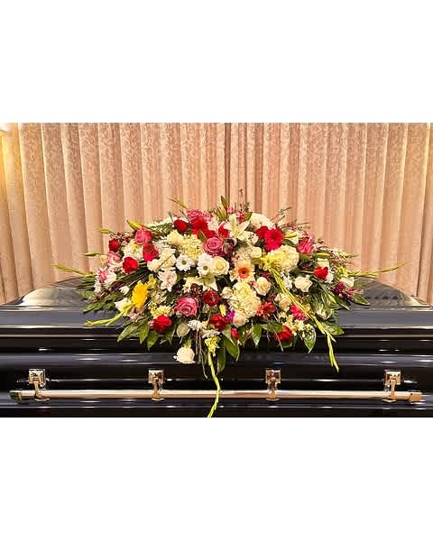 Large floral spray on a black casket with red, pink, and white blooms
