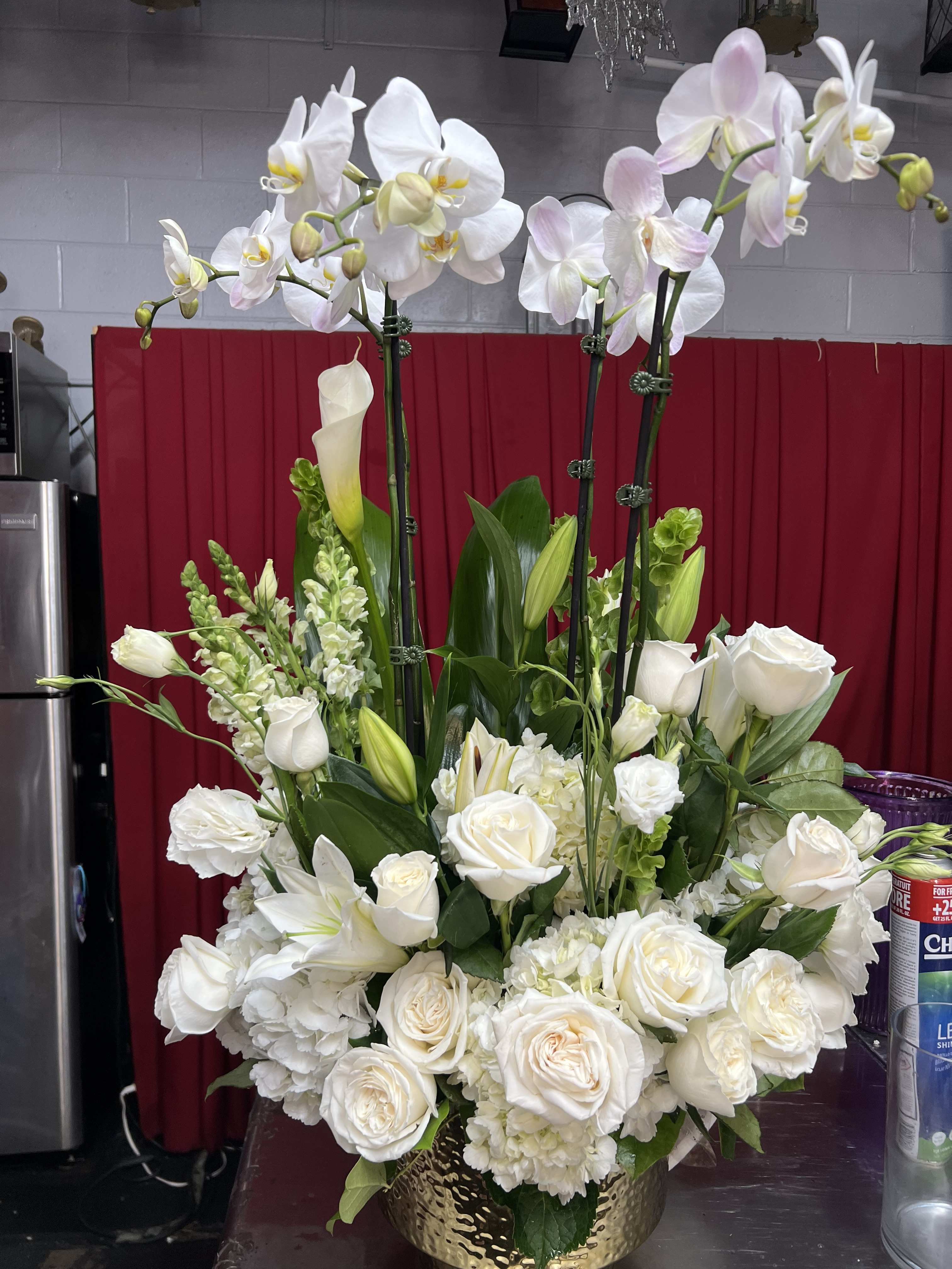 White orchid and rose arrangement in a gold vase