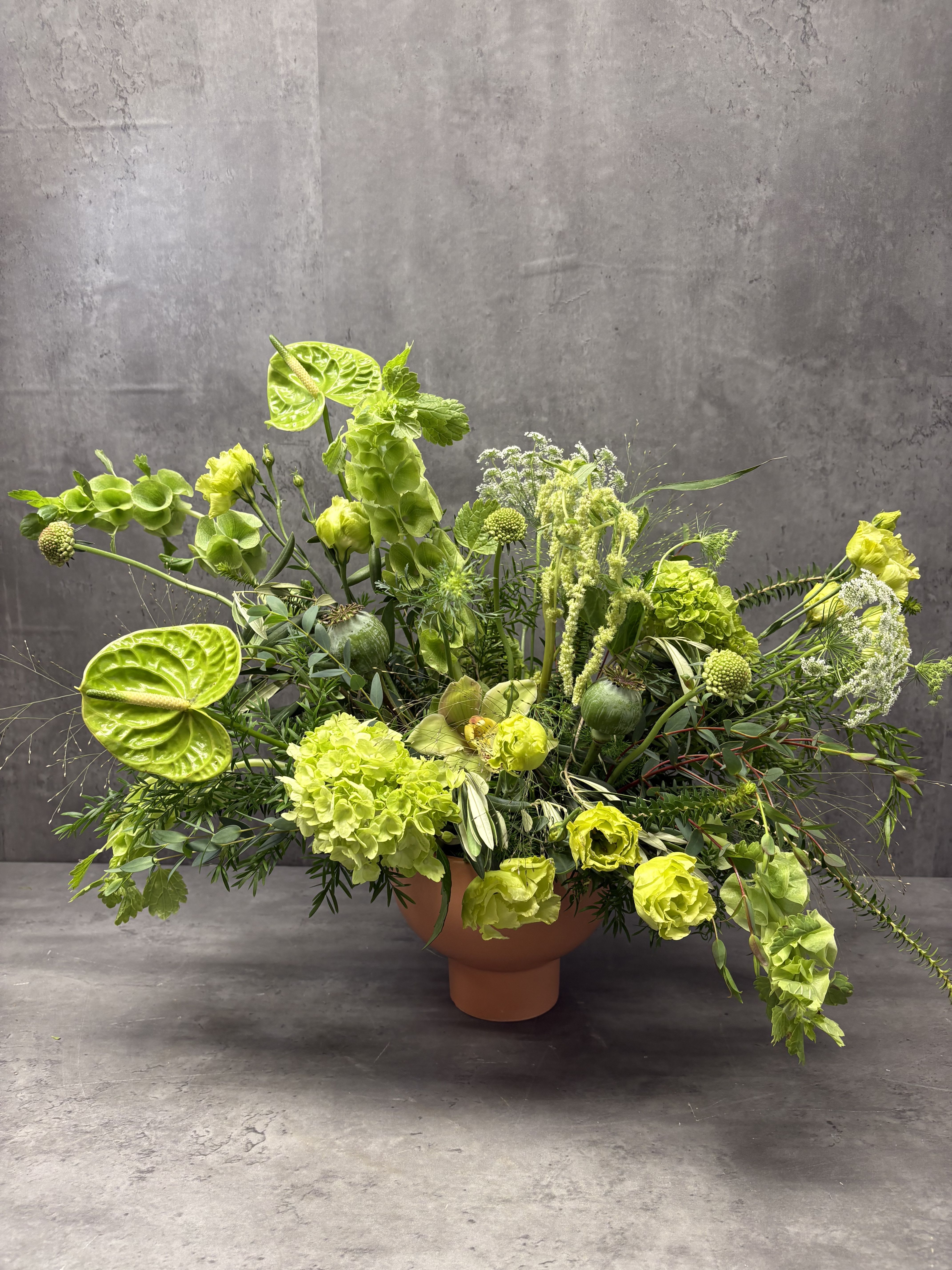 Lime-green floral arrangement in a terracotta pedestal vase