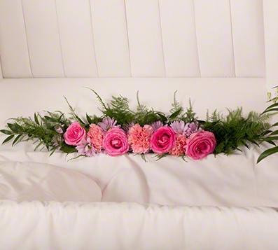Pink roses and carnations arranged with greenery on a white couch