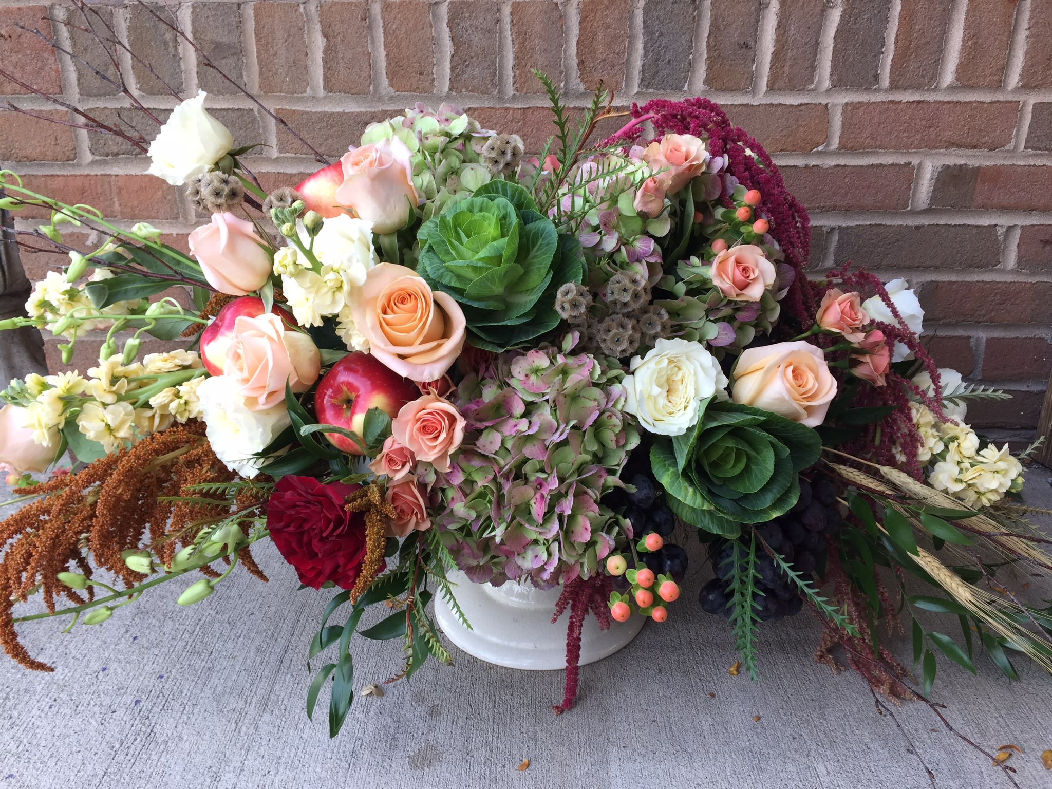 Mixed bouquet with roses, hydrangeas, and apples in a white vase