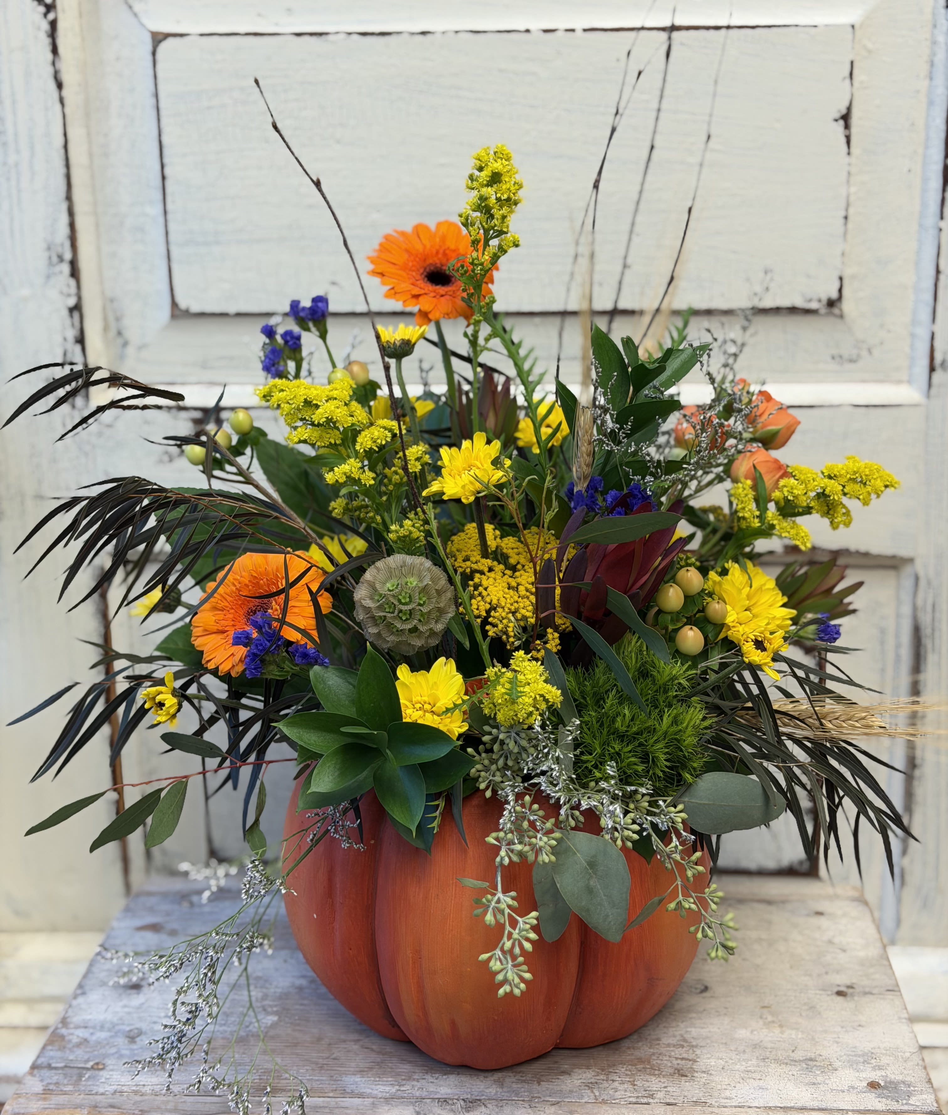 Mixed orange and yellow flowers arranged in a pumpkin-shaped container