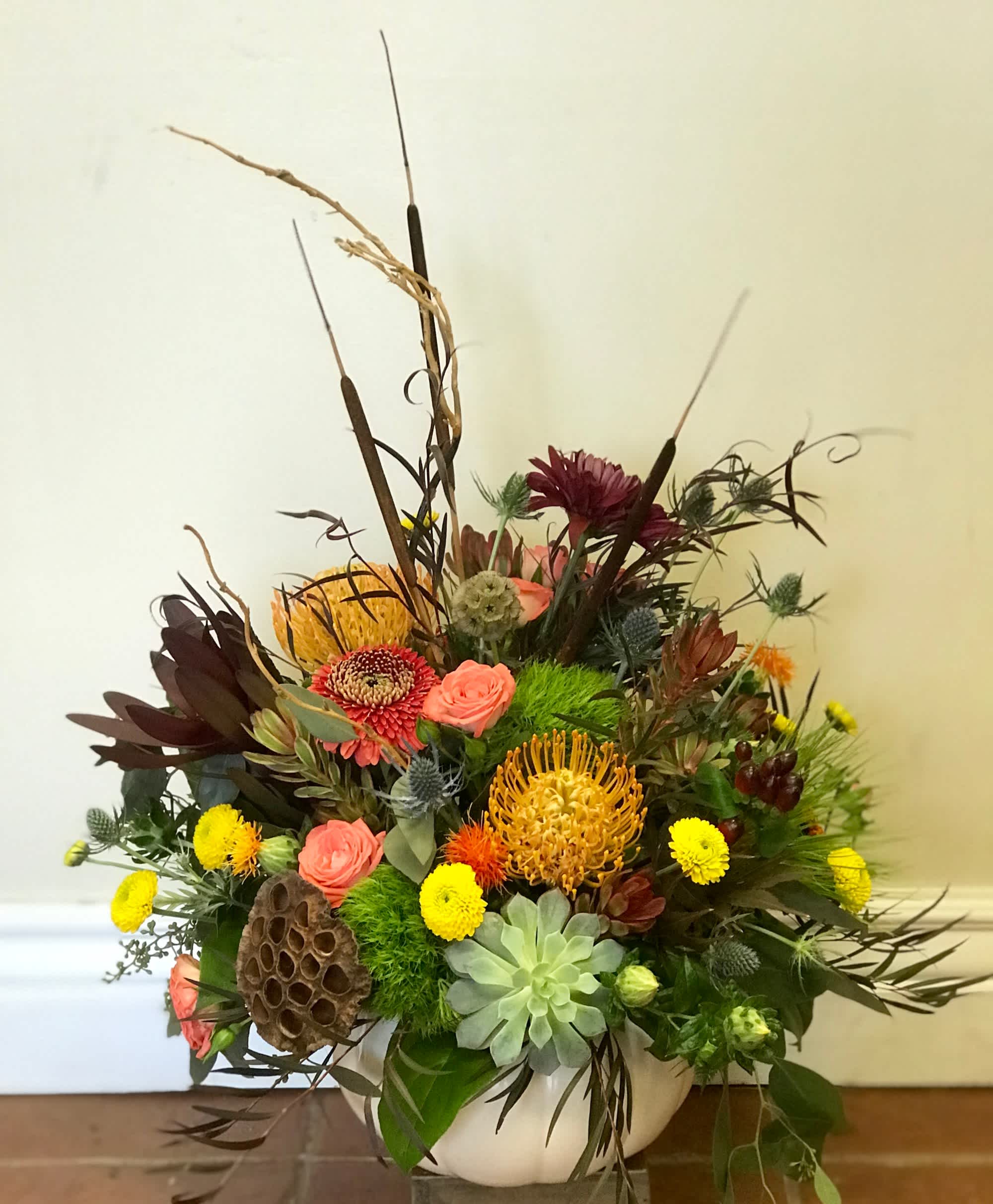 Mixed floral arrangement in a white bowl vase with tall dried accents