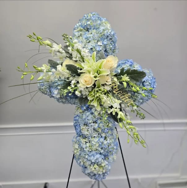 Blue and white floral cross arrangement on a stand
