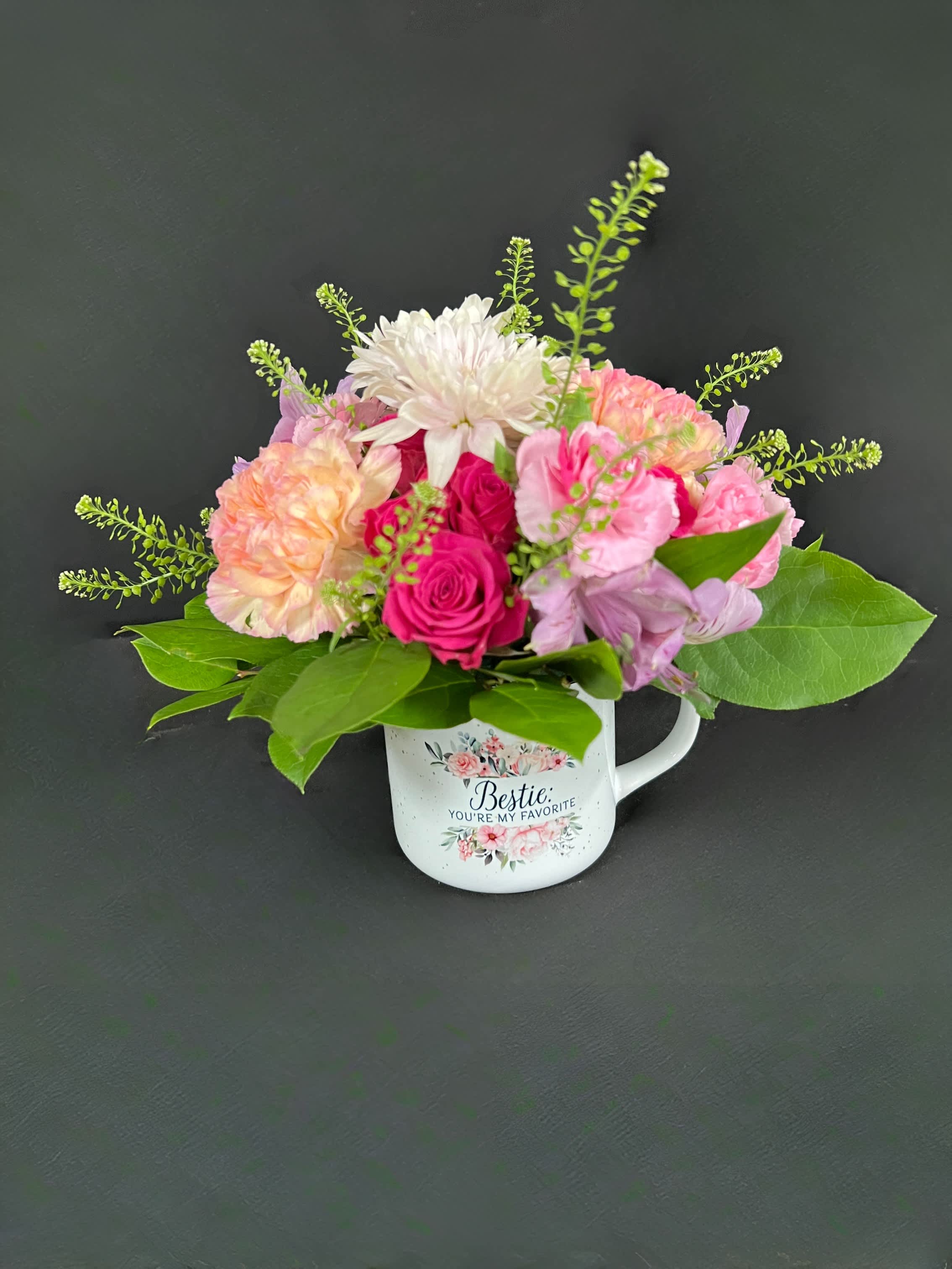 Pink and white flower arrangement in a decorative mug