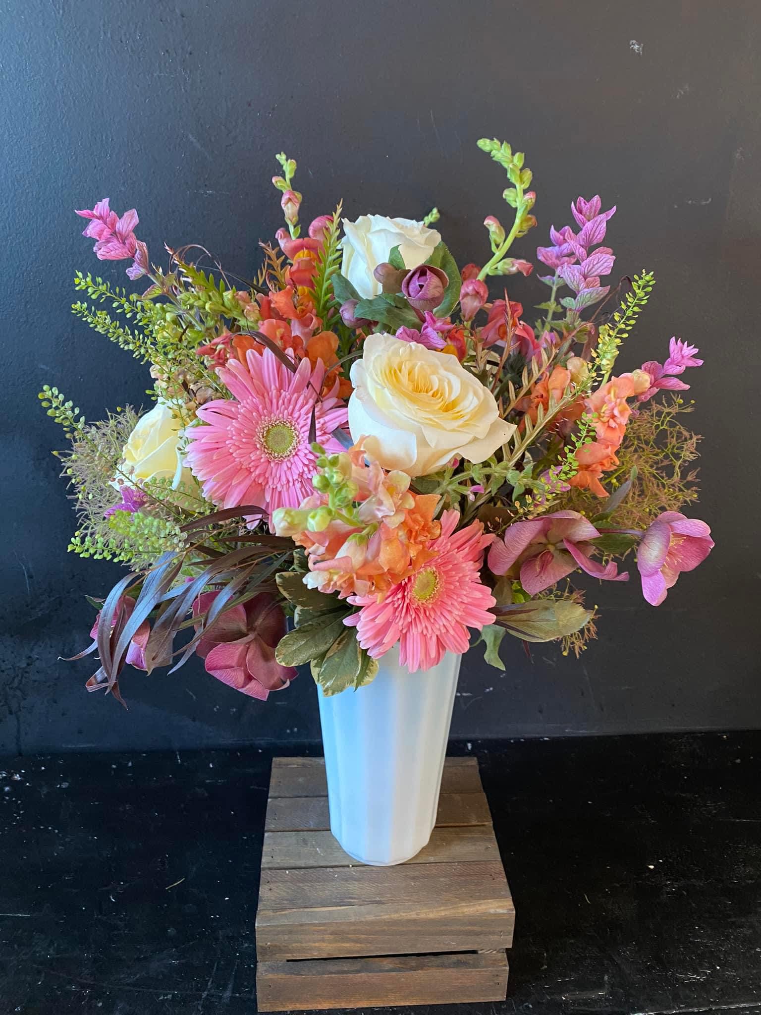 Pink and white mixed flower arrangement in a tall white vase