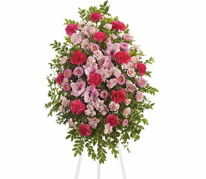 Standing floral spray of pink and red flowers on a white easel