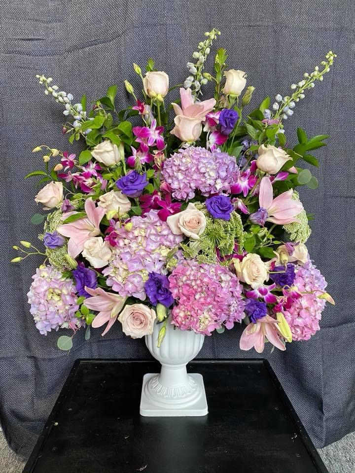 Large pastel floral arrangement in a white pedestal vase