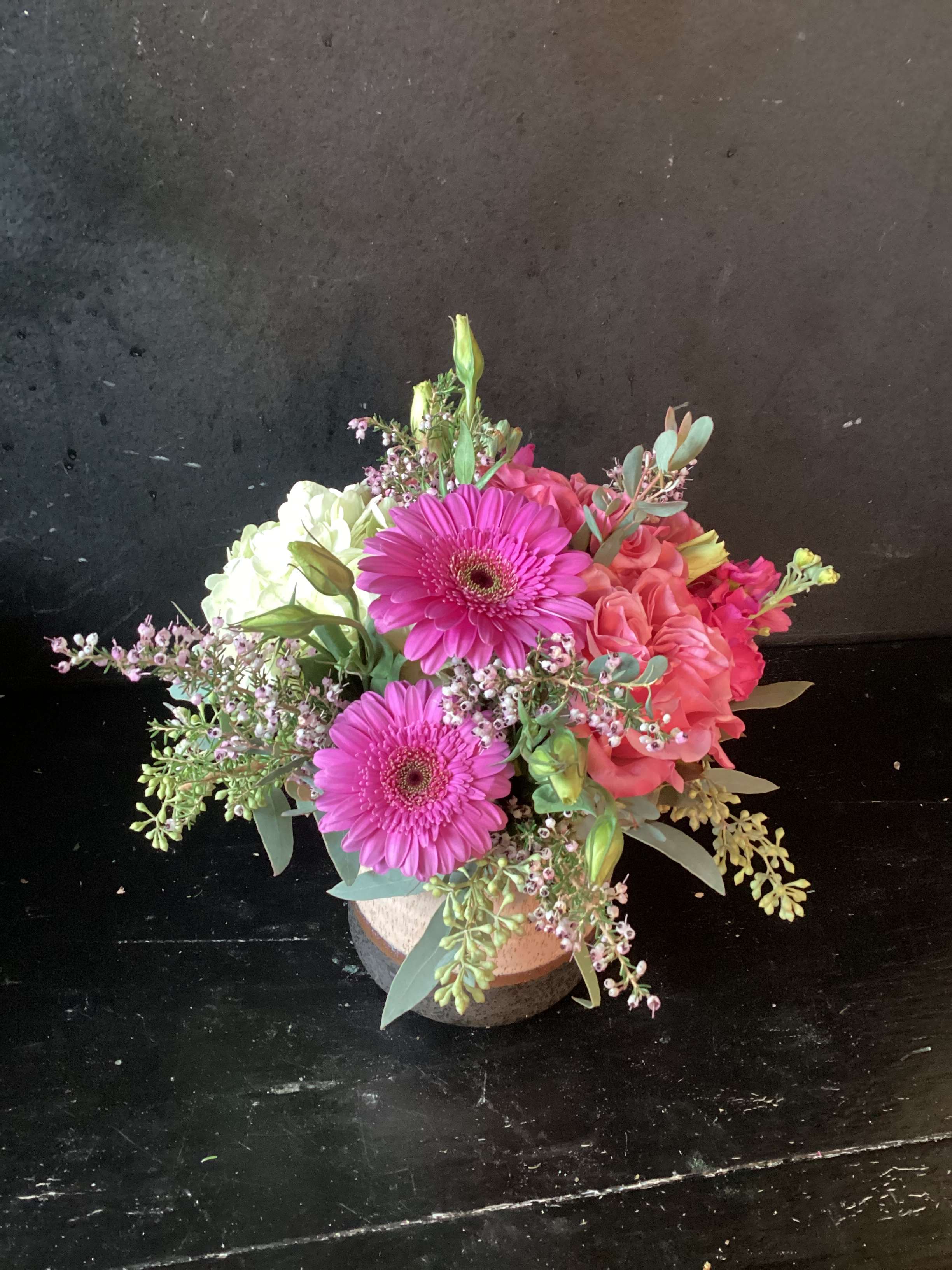 Bouquet of pink gerbera daisies and roses in a low round container