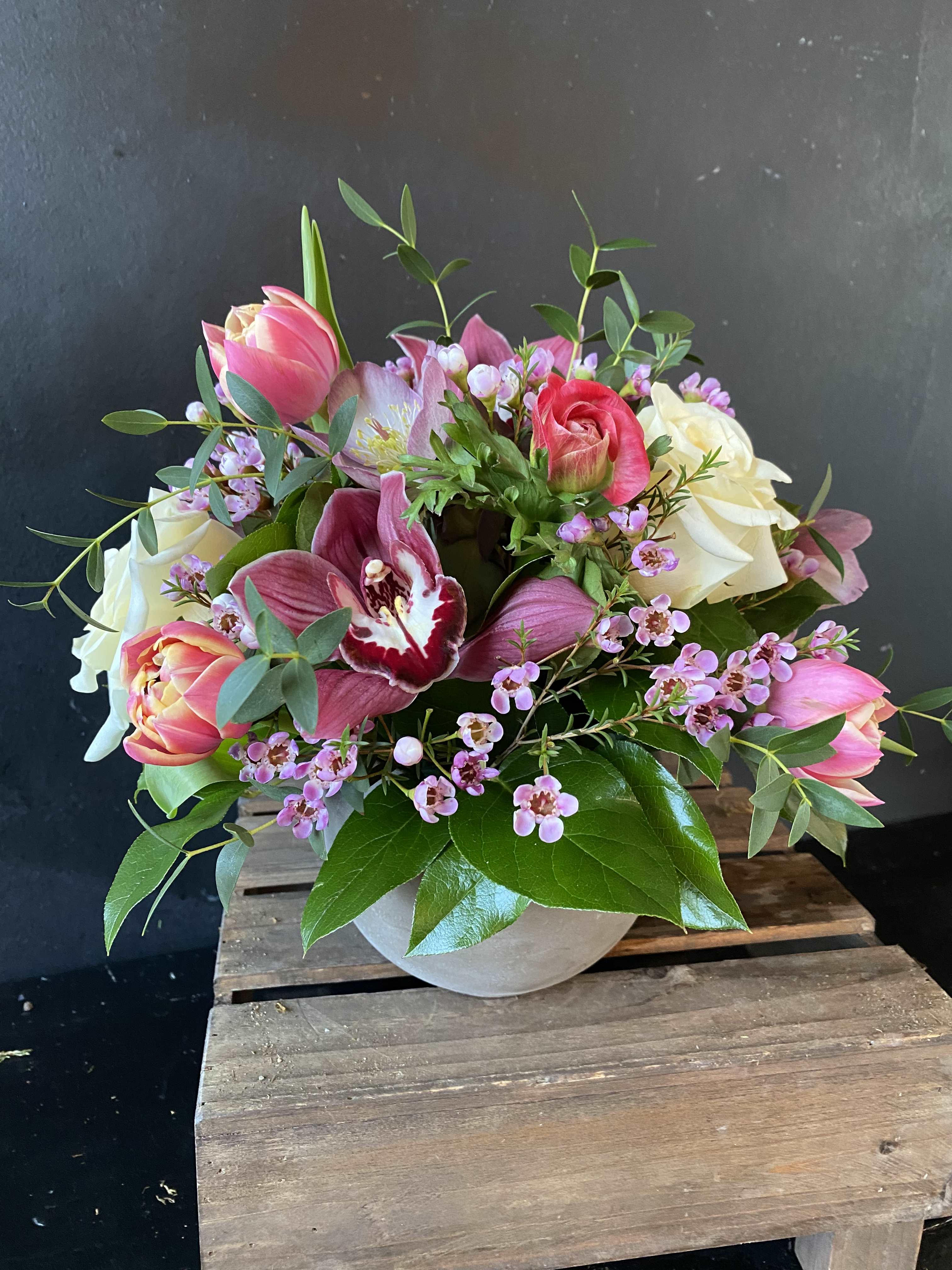 Pink and white tulips with roses and orchids in a round vase