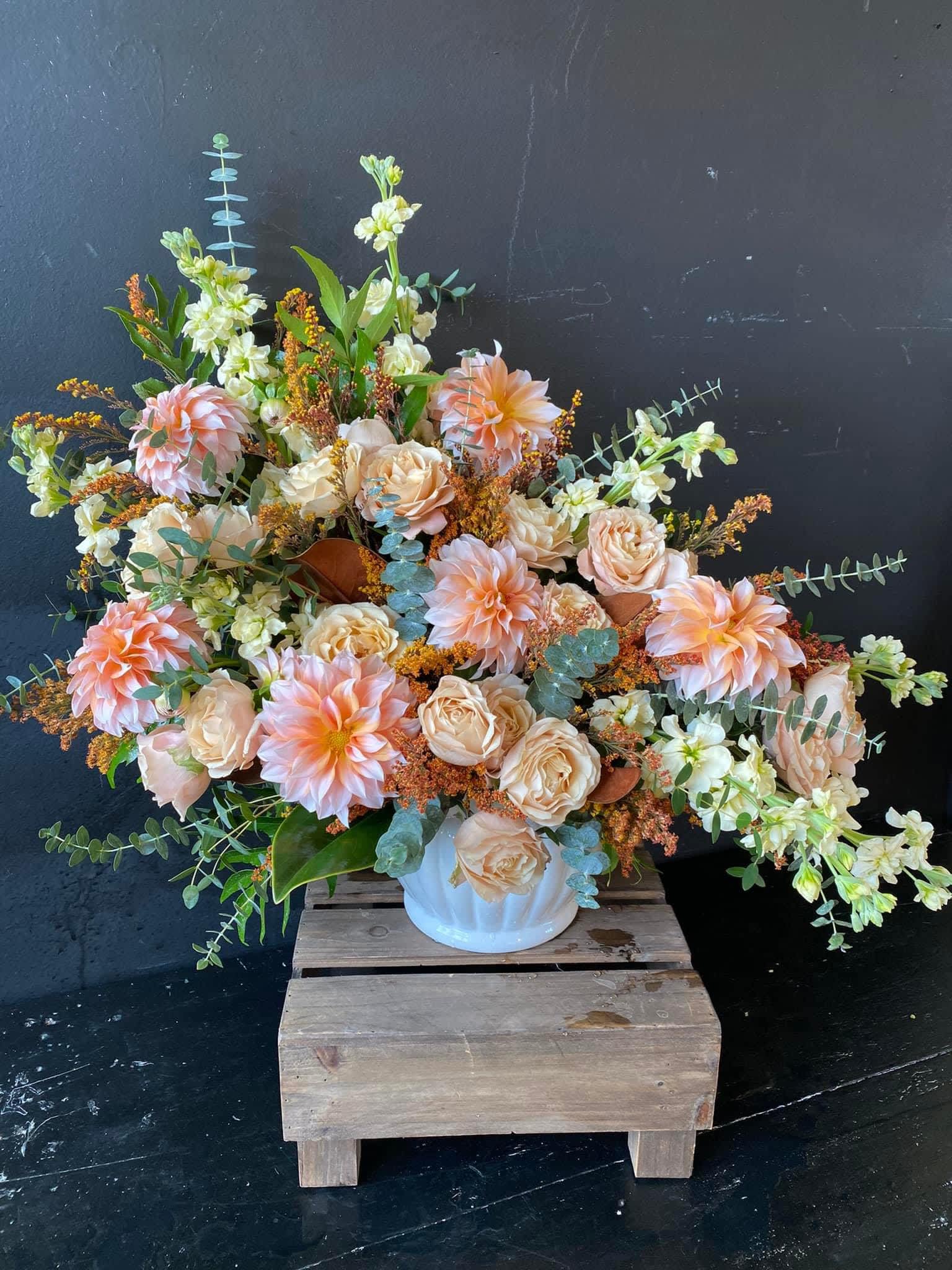 Large peach and cream floral arrangement in a white vase