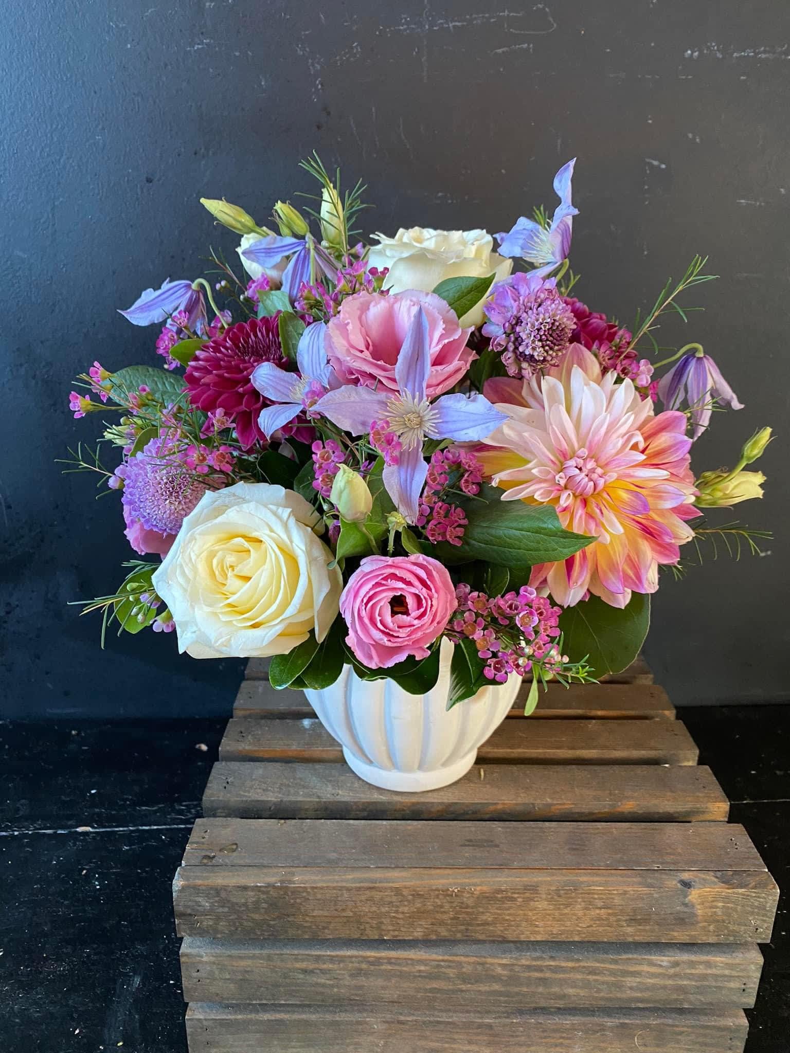Mixed bouquet in a white vase with roses, dahlias, and pastel blooms