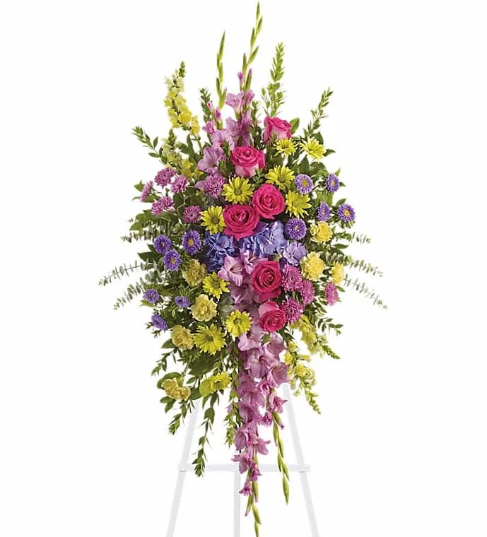 Tall standing floral spray with pink roses and purple flowers on an easel