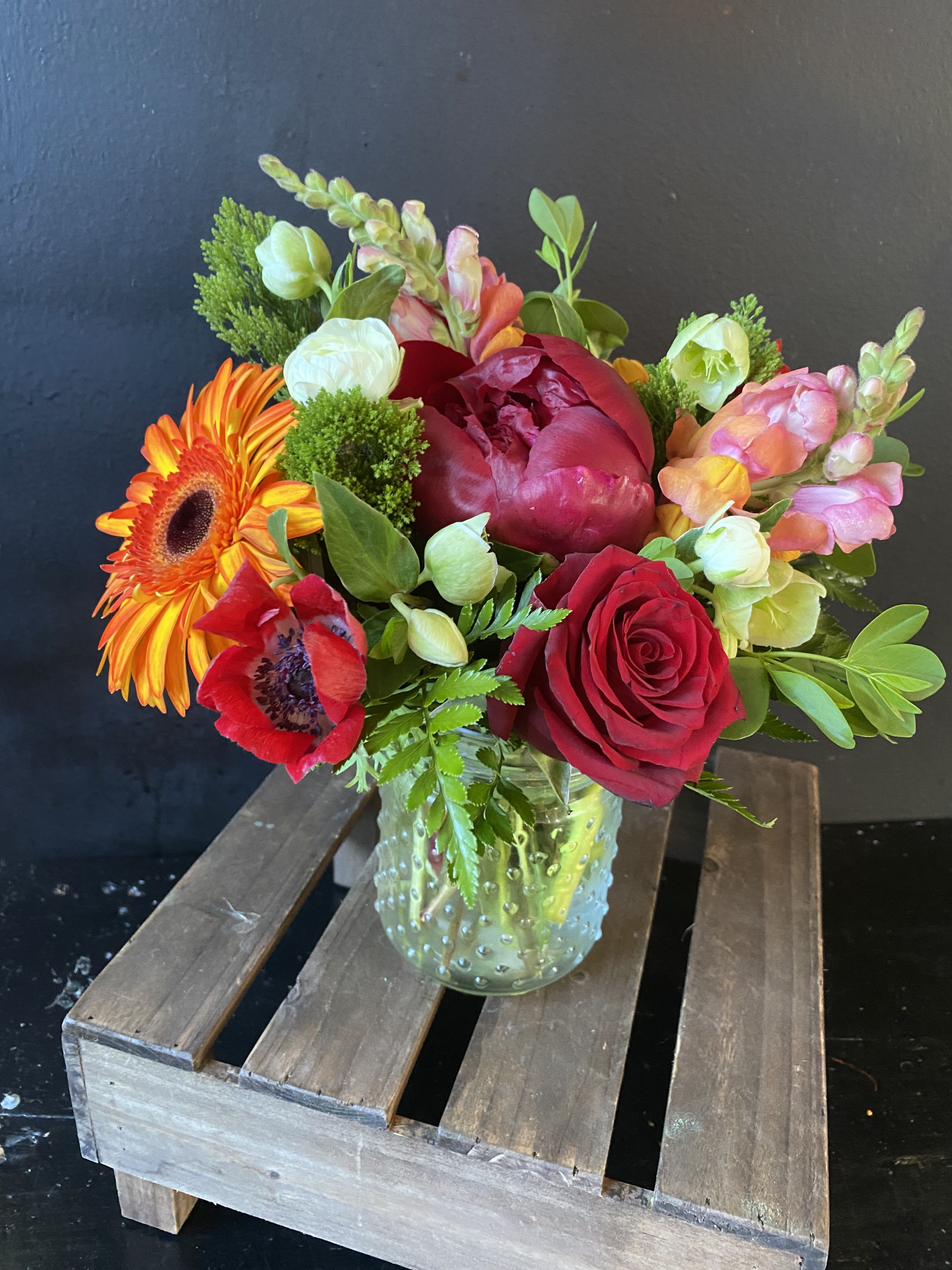 Mixed bouquet in a clear glass vase with red, orange, pink, and white blooms