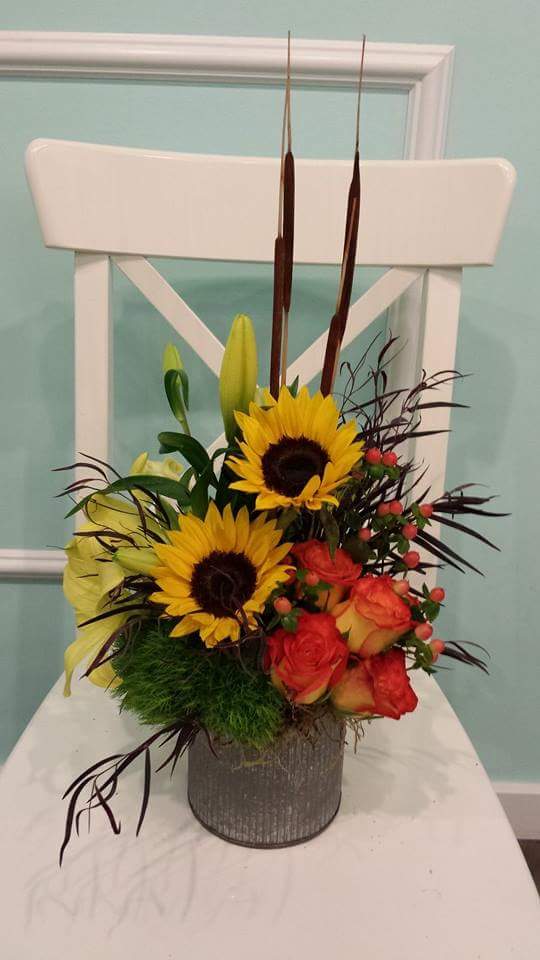 Sunflowers, roses, and lilies arranged in a gray vase