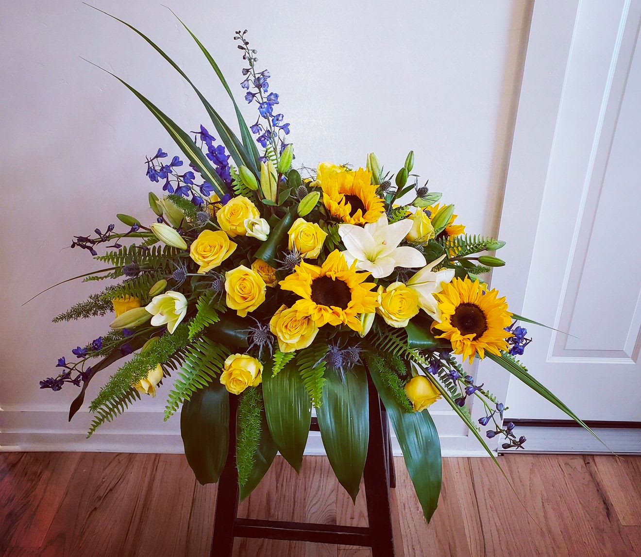 Yellow roses, sunflowers, and white lilies in a low arrangement