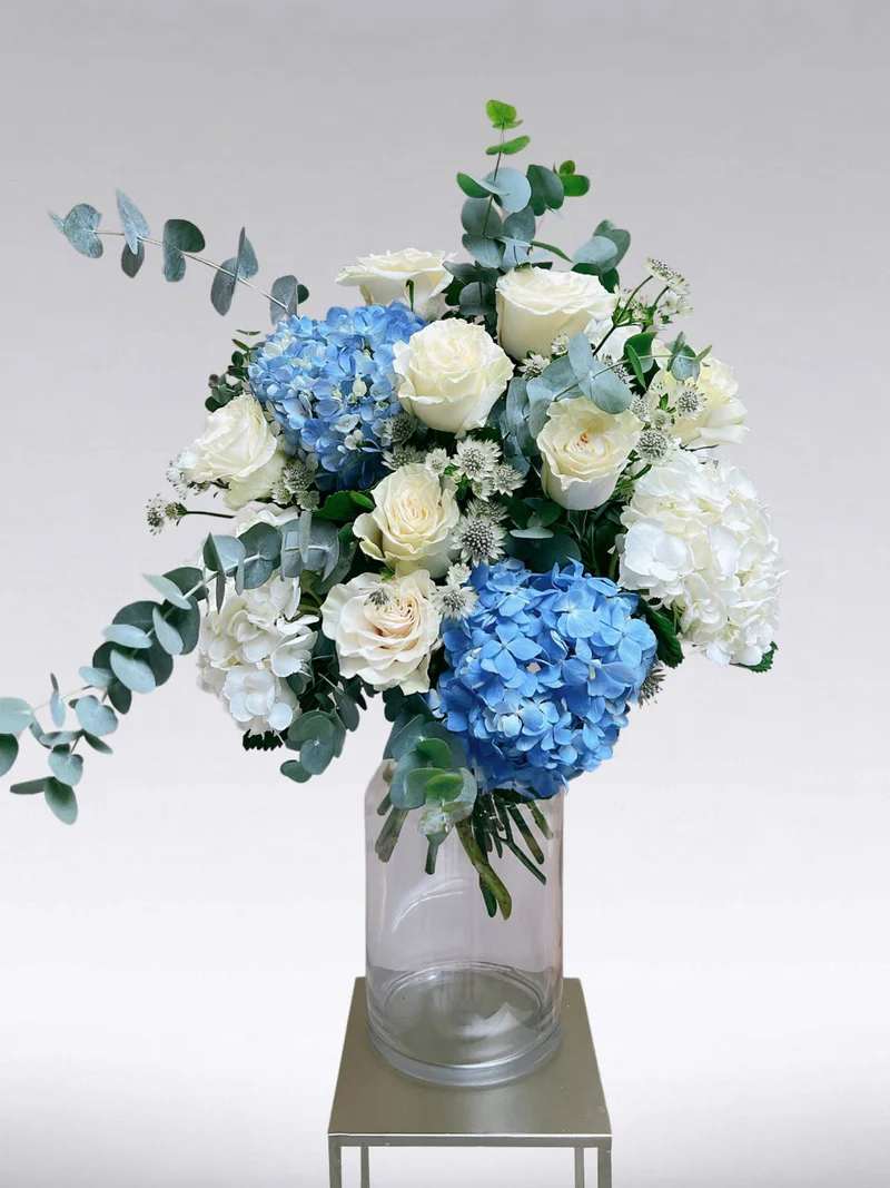 fresh summer day - A stunning bouquet of white roses, blue and white hydrangeas, and eucalyptus, capturing the essence of a fresh summer day. This enchanting arrangement will serenade your senses and bring a touch of Mediterranean charm to your loved one's heart.