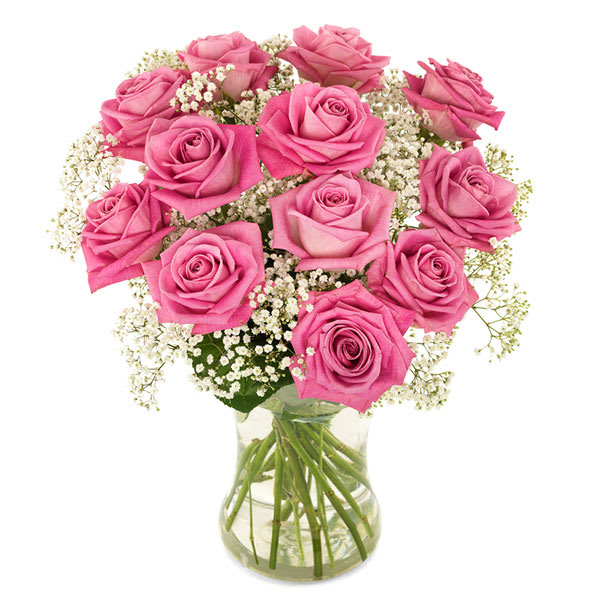 Arrangement of pink roses with white filler flowers in a clear glass vase