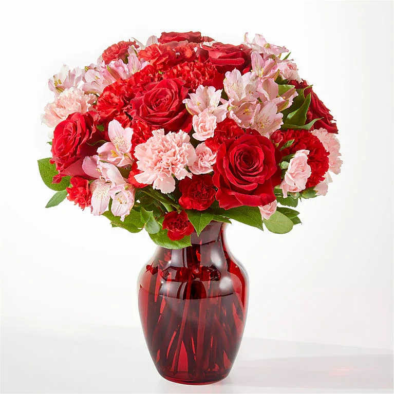 Red roses and pink carnations in a red glass vase