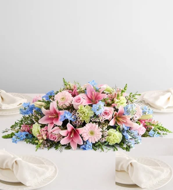 Pink lilies, roses, and blue flowers arranged on a white table