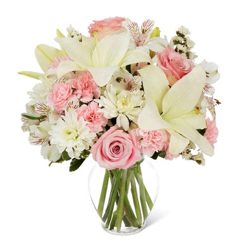 Pink roses and white lilies in a clear glass vase