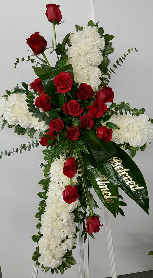 Cross-shaped floral spray with red roses and white blooms on an easel
