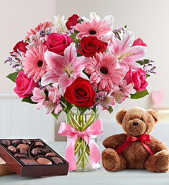 Pink and red mixed bouquet in a glass vase with a teddy bear and chocolates