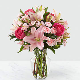 Pink lilies and roses arranged in a clear glass vase