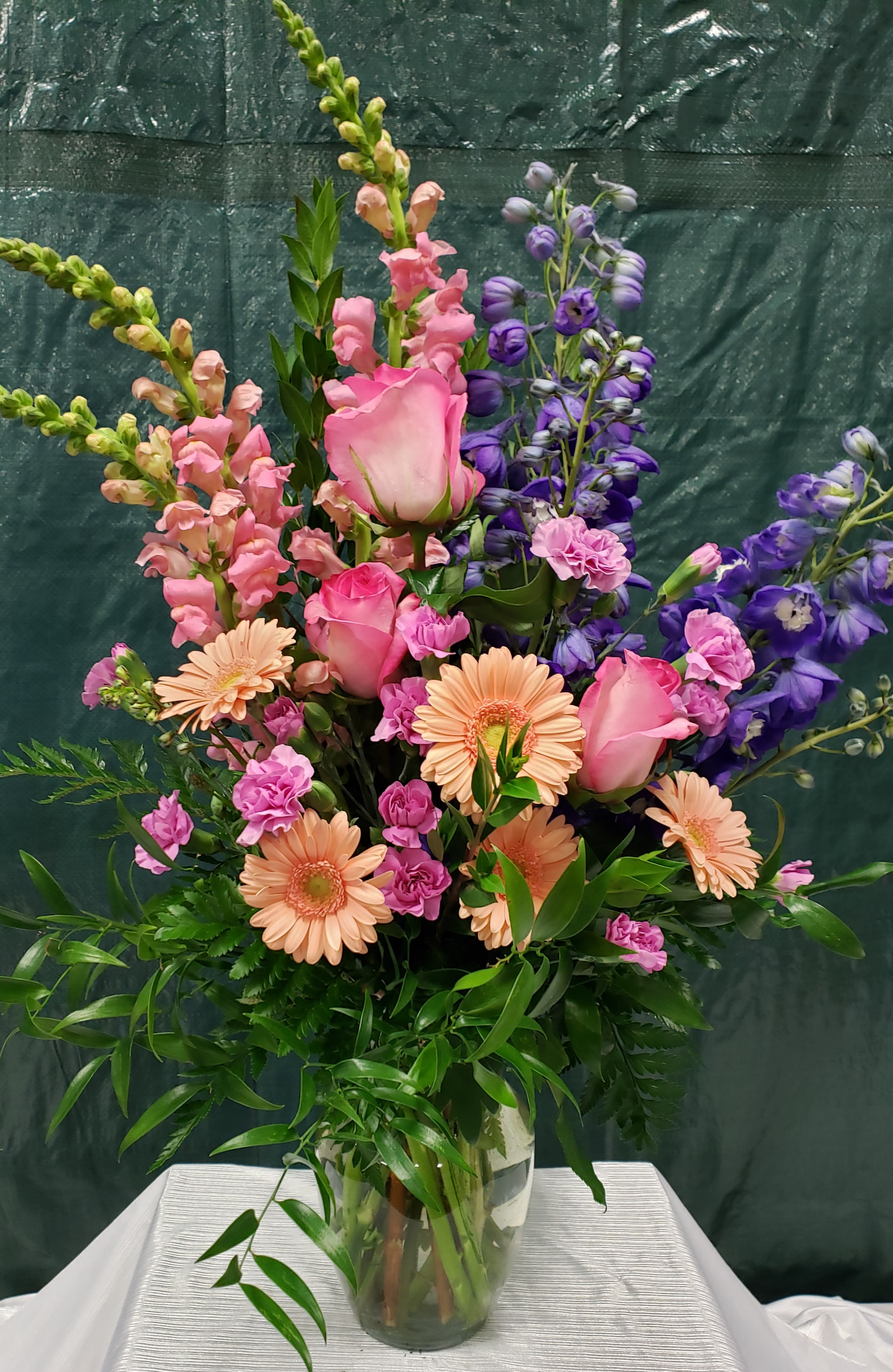 Tall mixed bouquet in a glass vase with pink roses and peach daisies