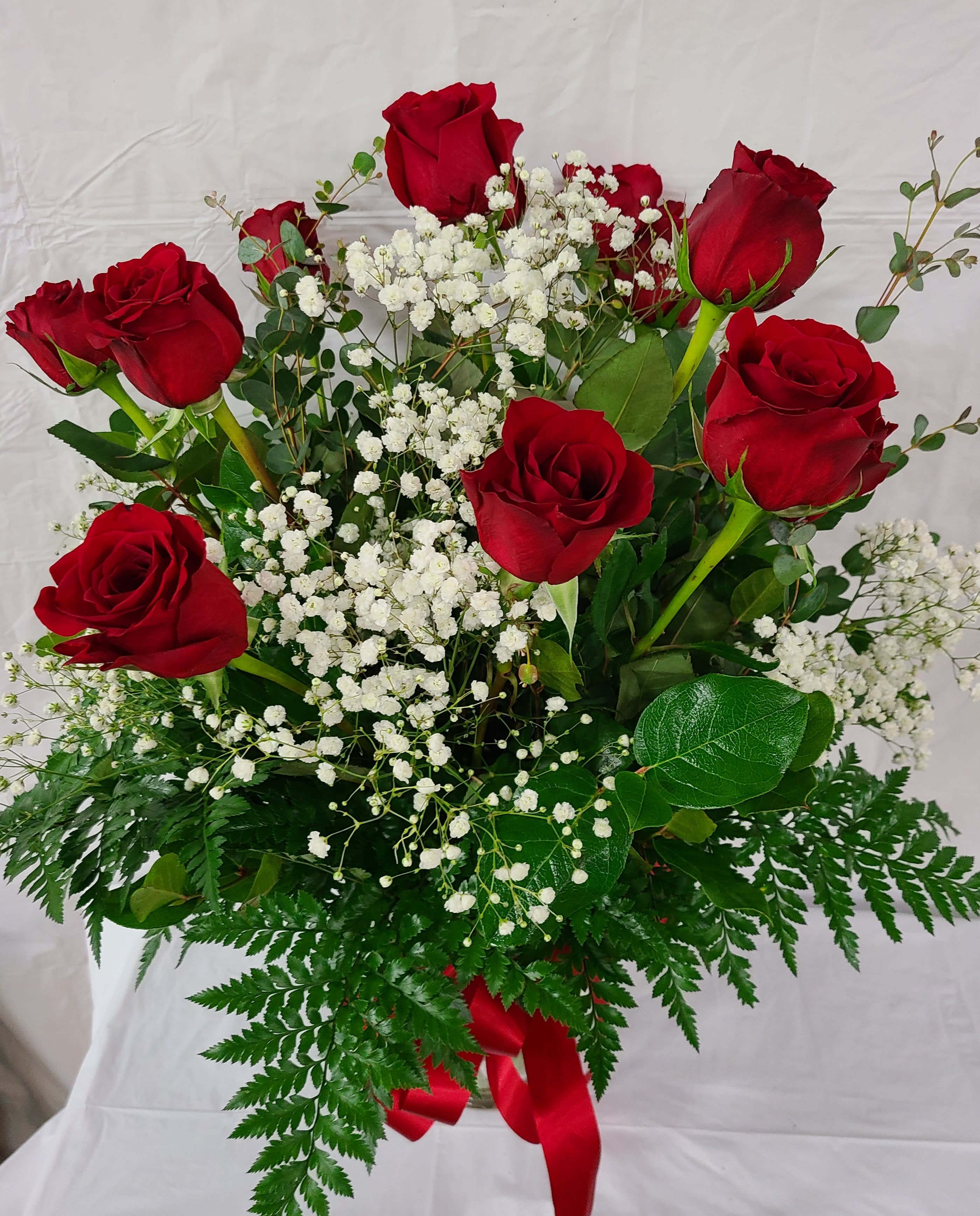 Red roses with white baby's breath in a bouquet with fern foliage