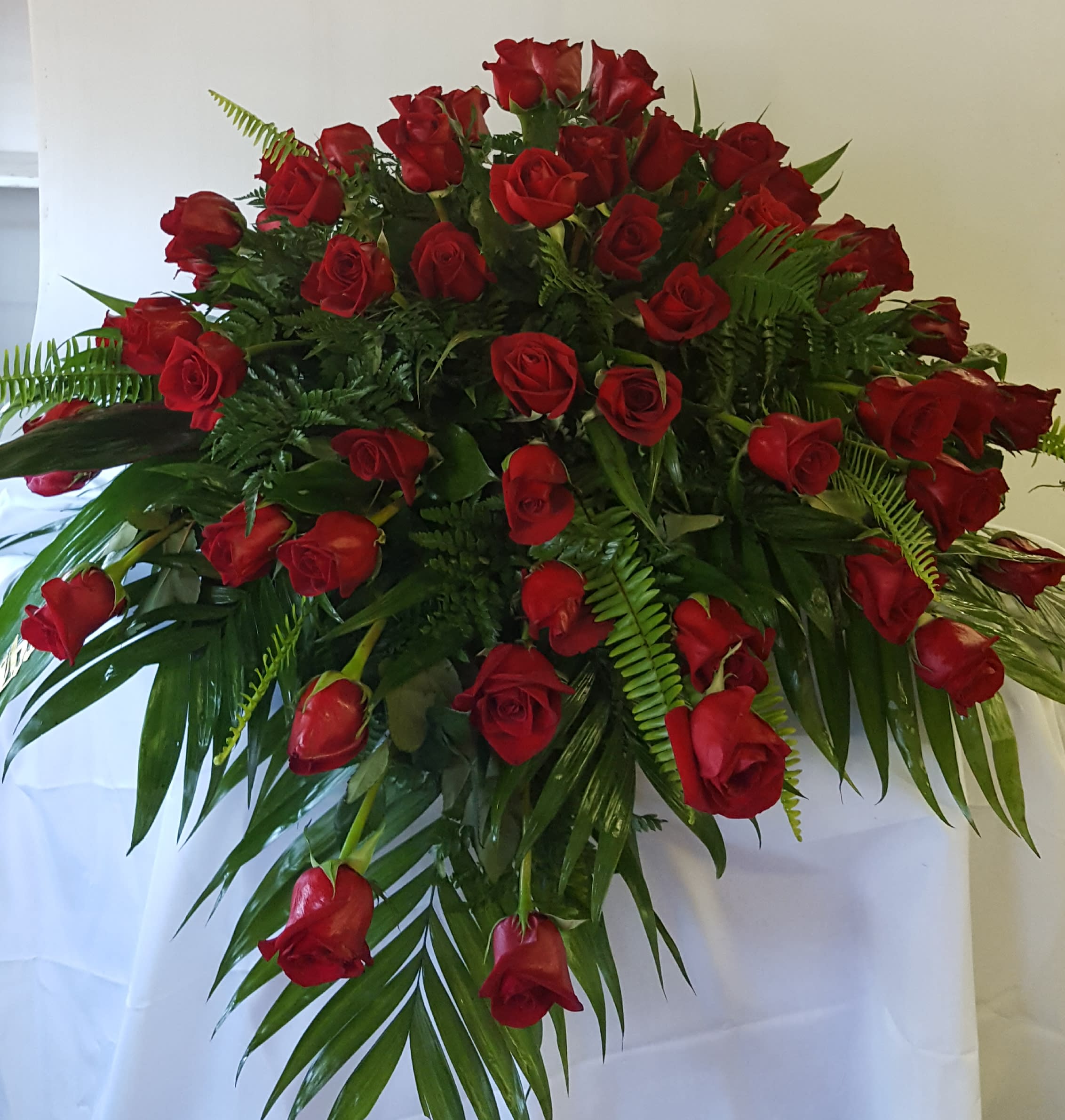 Large bouquet of red roses with palm fronds and fern greenery