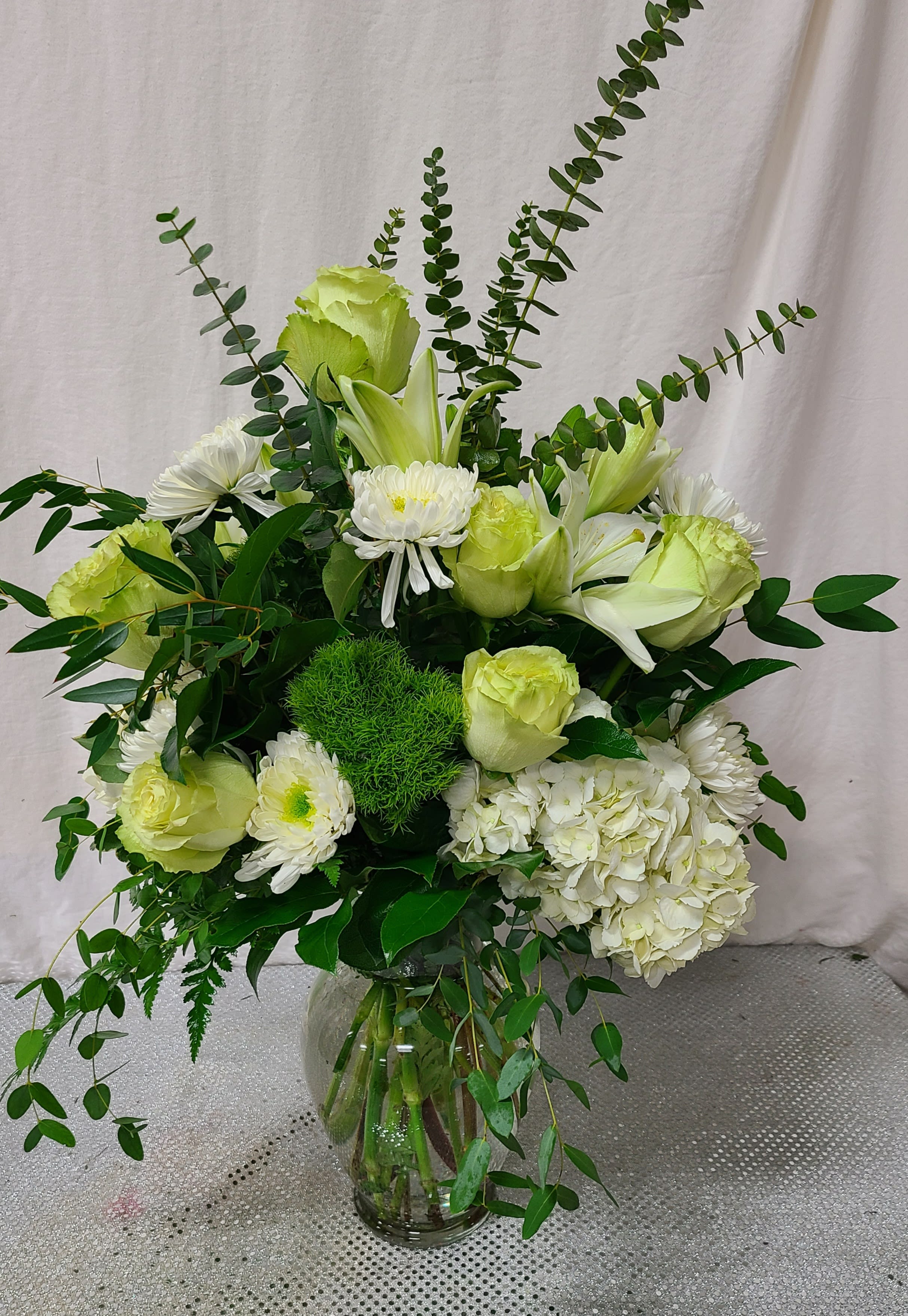 White and pale green floral arrangement in a glass vase