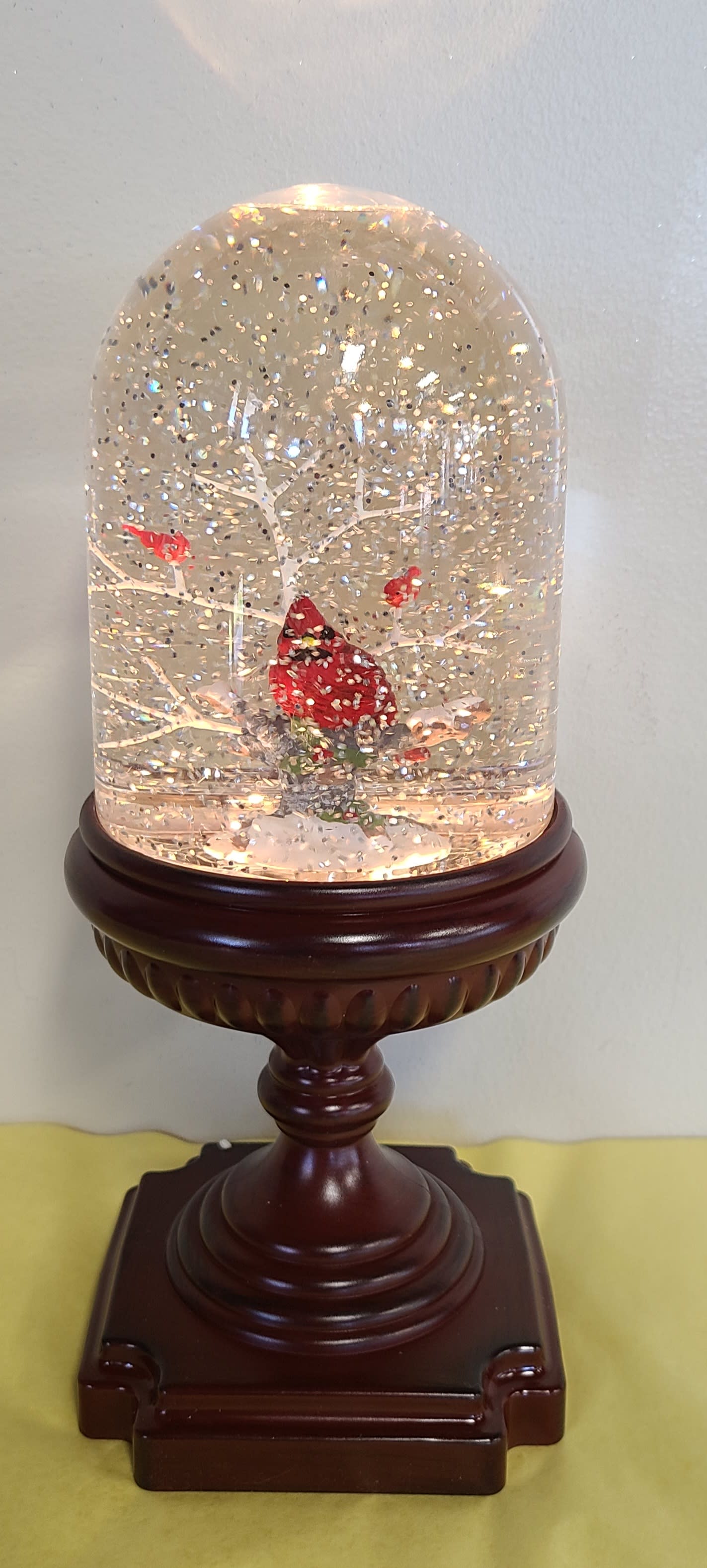 Snow globe with a red cardinal on a wooden pedestal