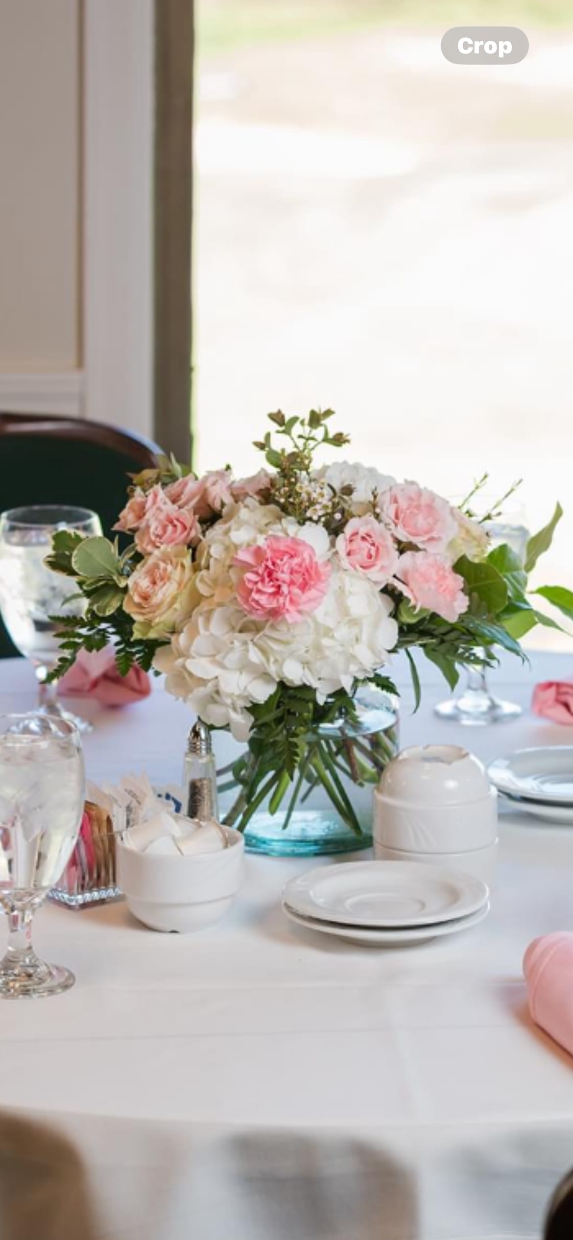 Pink and white floral centerpiece in a glass vase on a table
