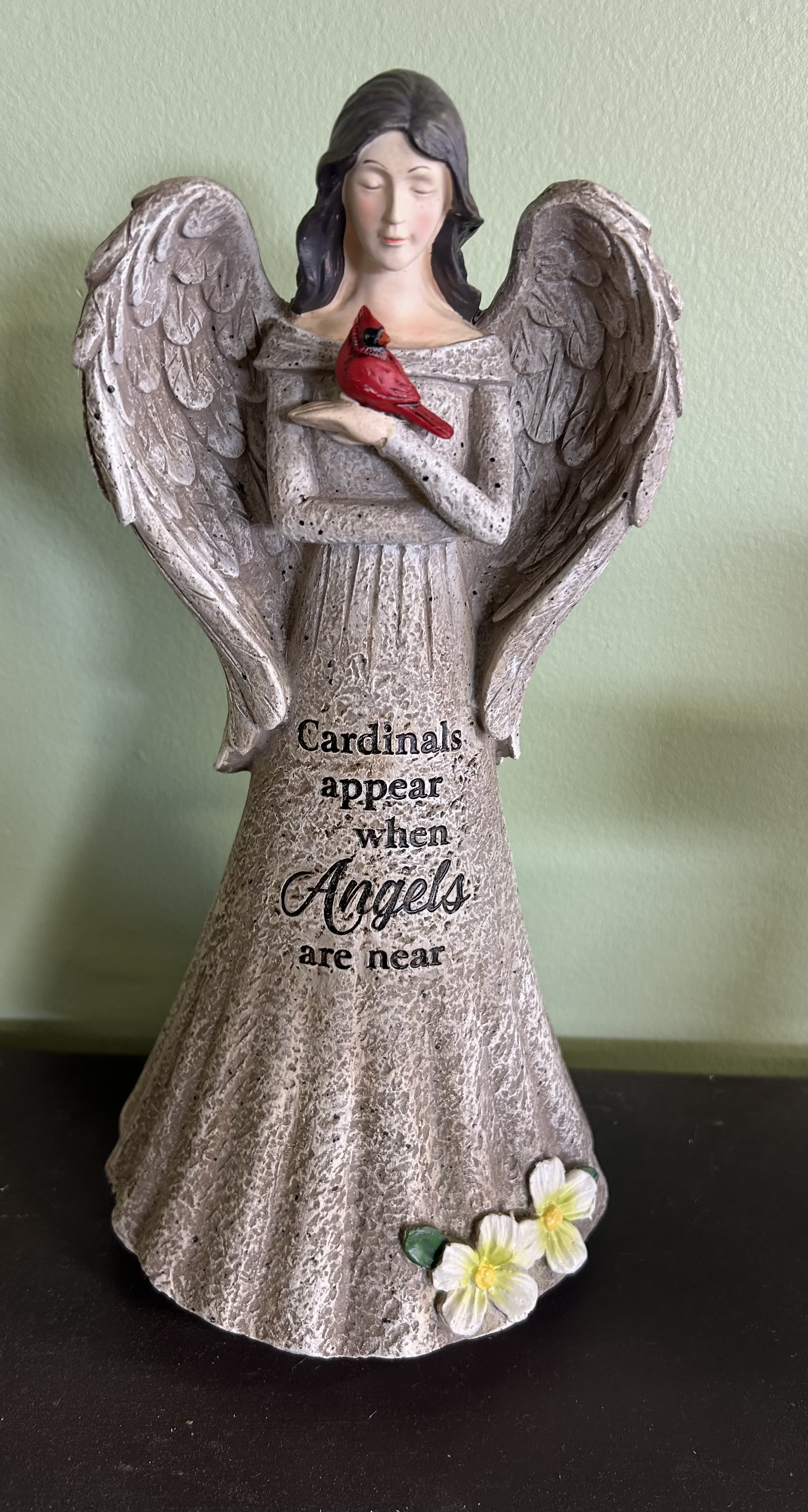 Angel figurine holding a red cardinal with text on the base