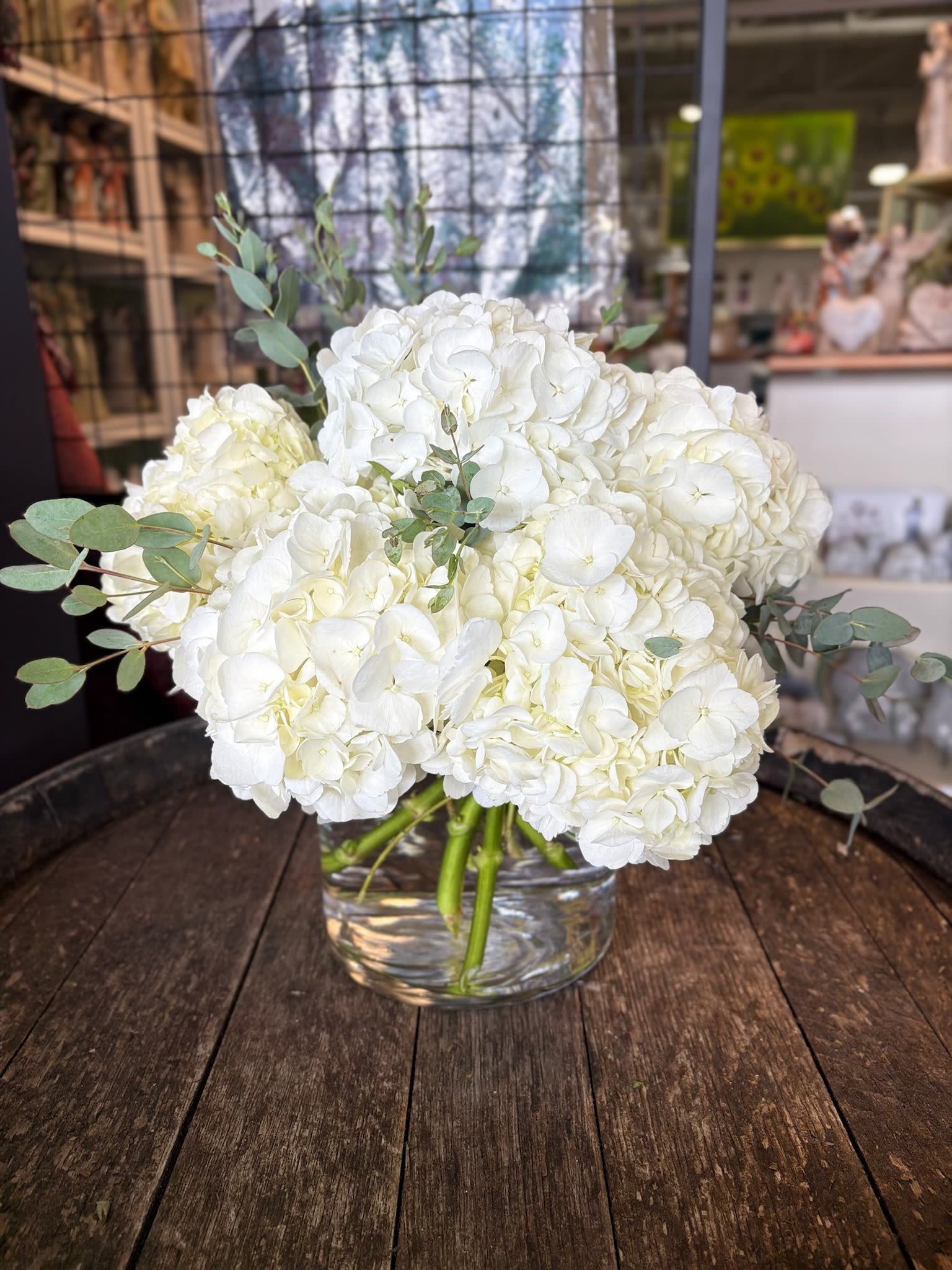 White hydrangea bouquet in a clear glass vase with eucalyptus