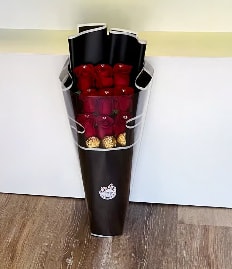 Bouquet of red roses wrapped in dark paper with gold accents