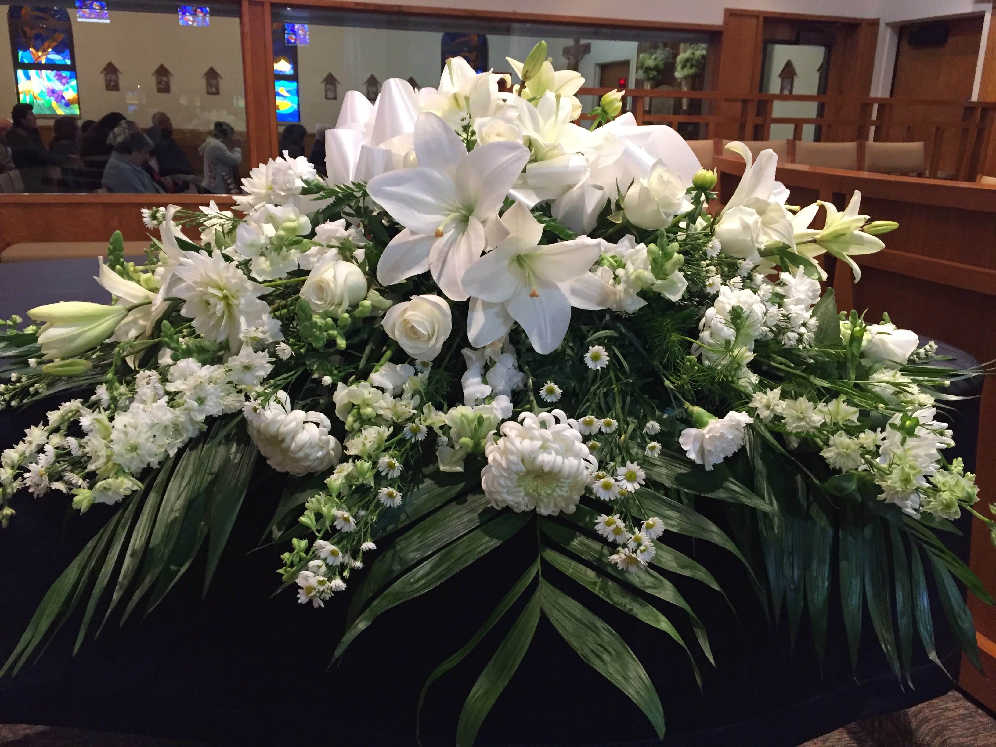 Large white floral arrangement with lilies and roses on a table