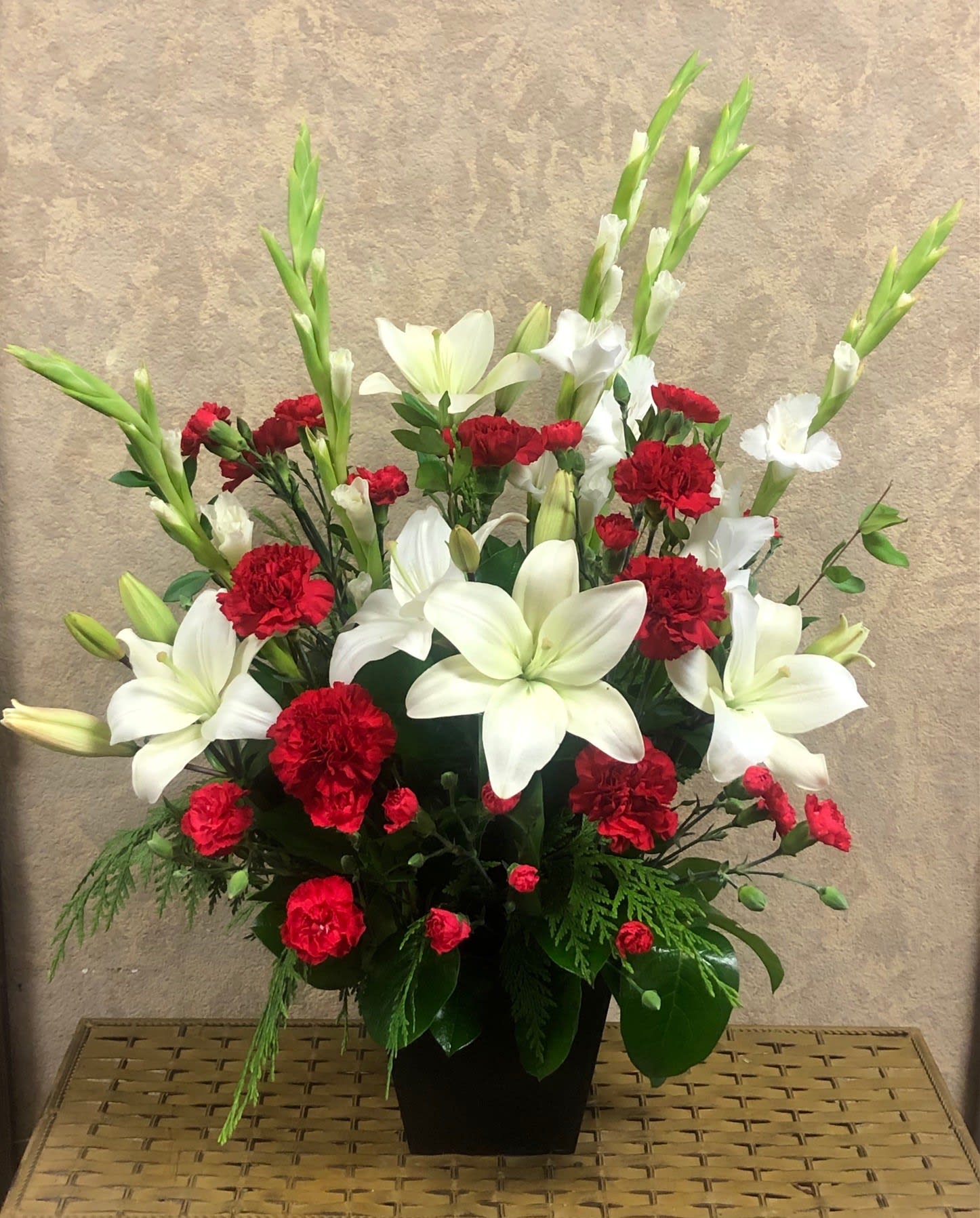 Red carnations and white lilies arranged in a black vase