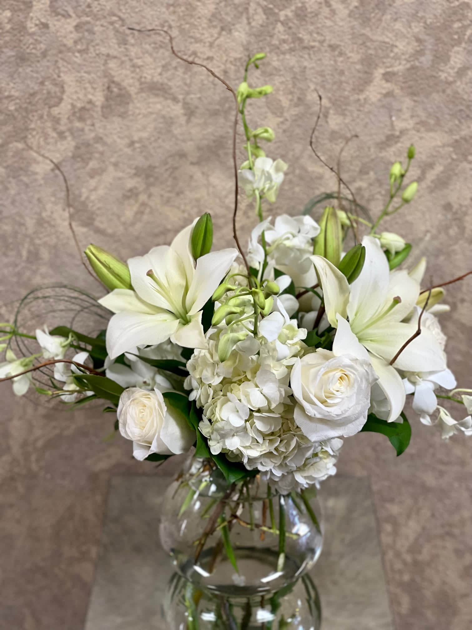 White lilies and roses arranged in a clear glass vase