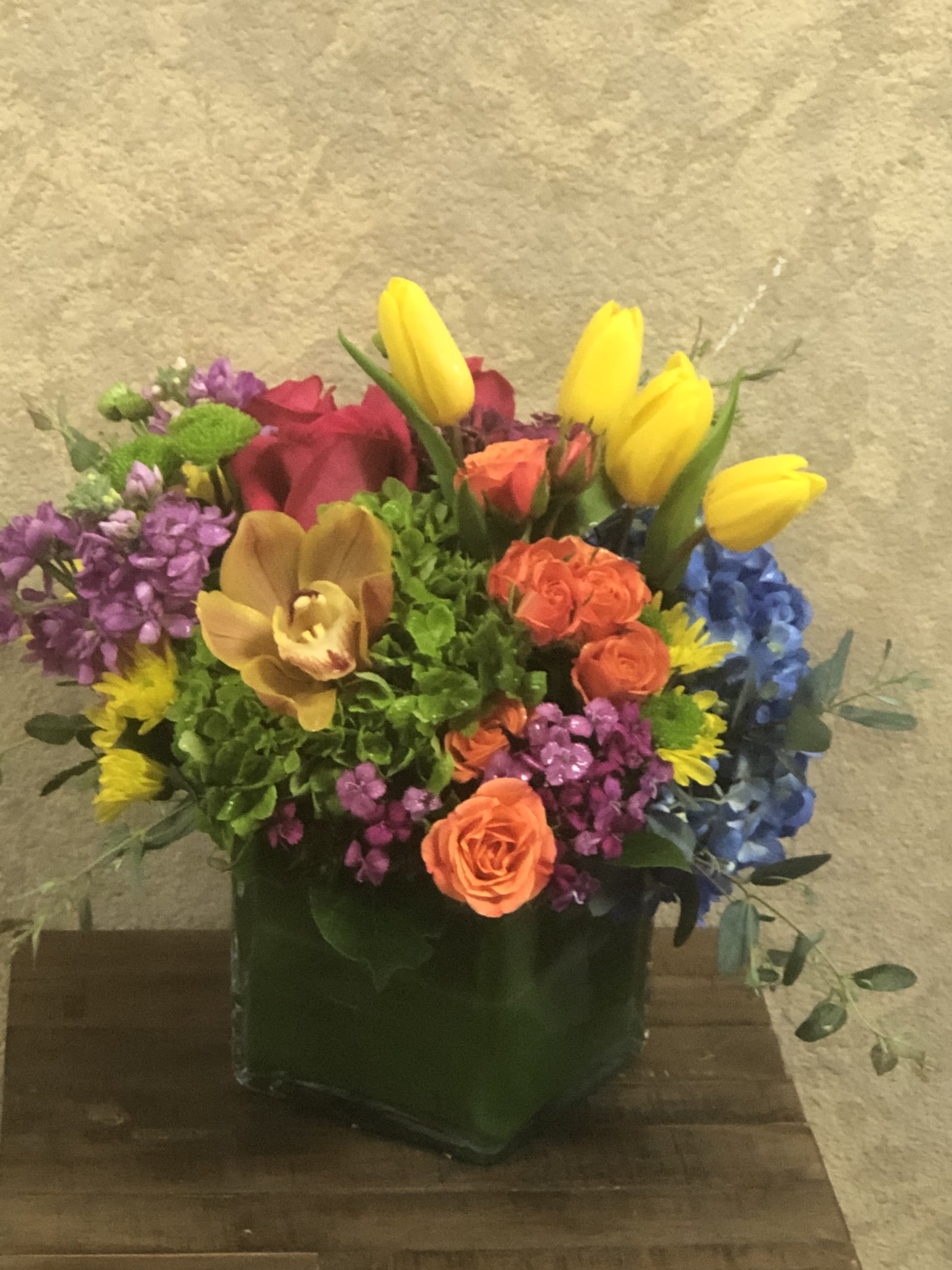 Colorful mixed flower arrangement in a square glass vase