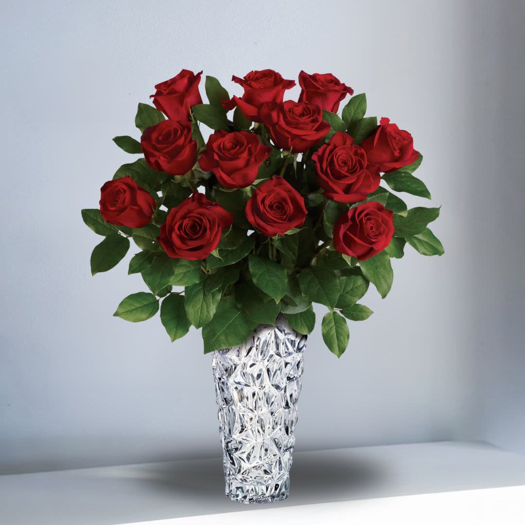 Arrangement of long-stem red roses in a tall textured clear glass vase