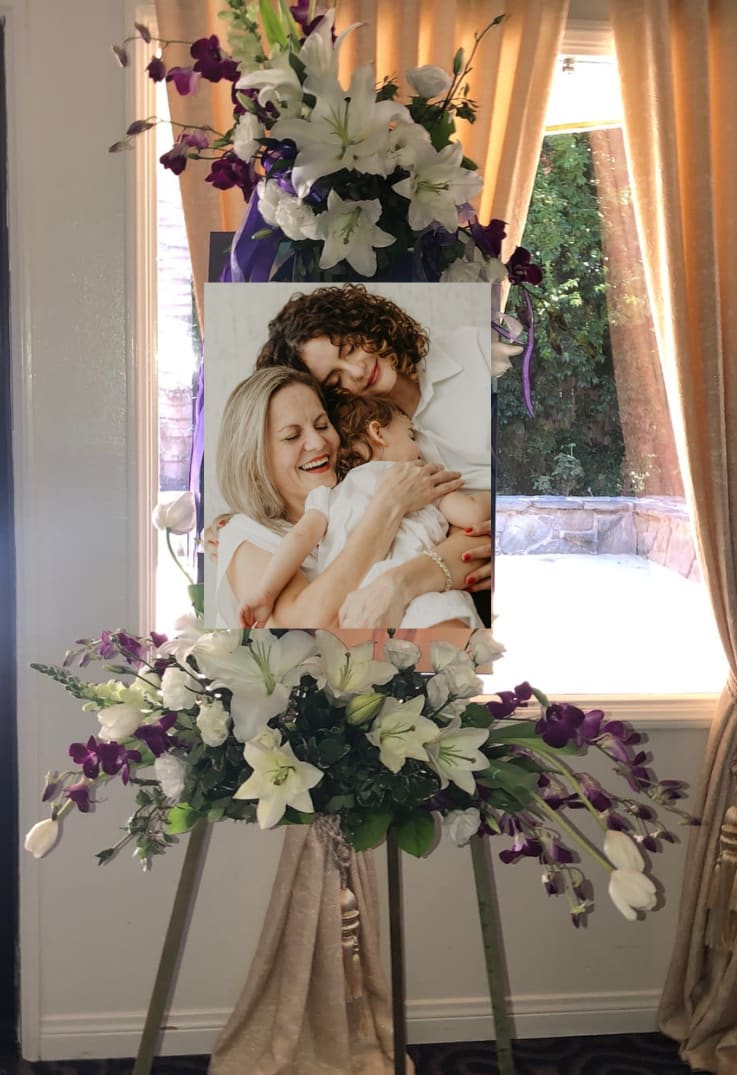 Standing floral easel with white lilies and purple orchids around a photo